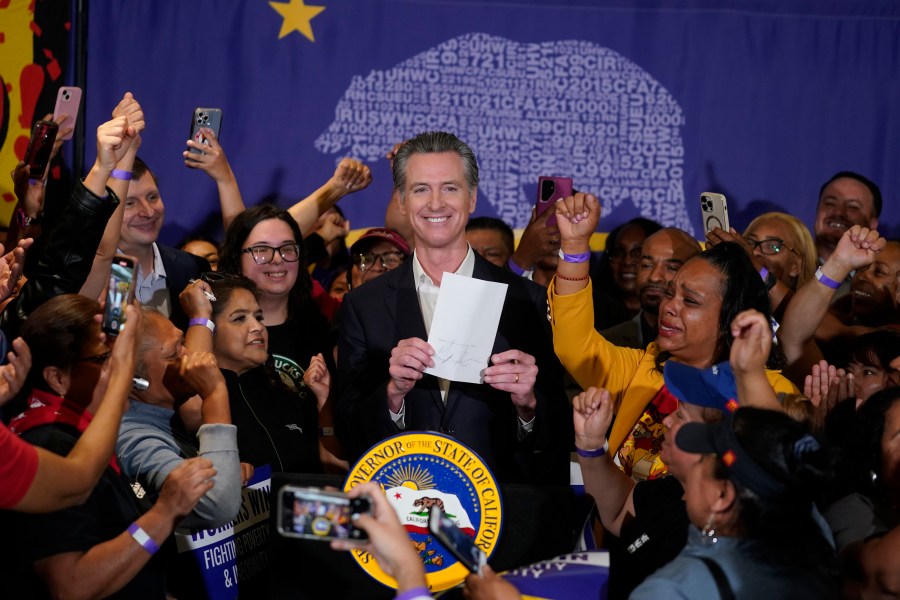 California Gov. Gavin Newsom signs the fast food bill surrounded by fast food workers.