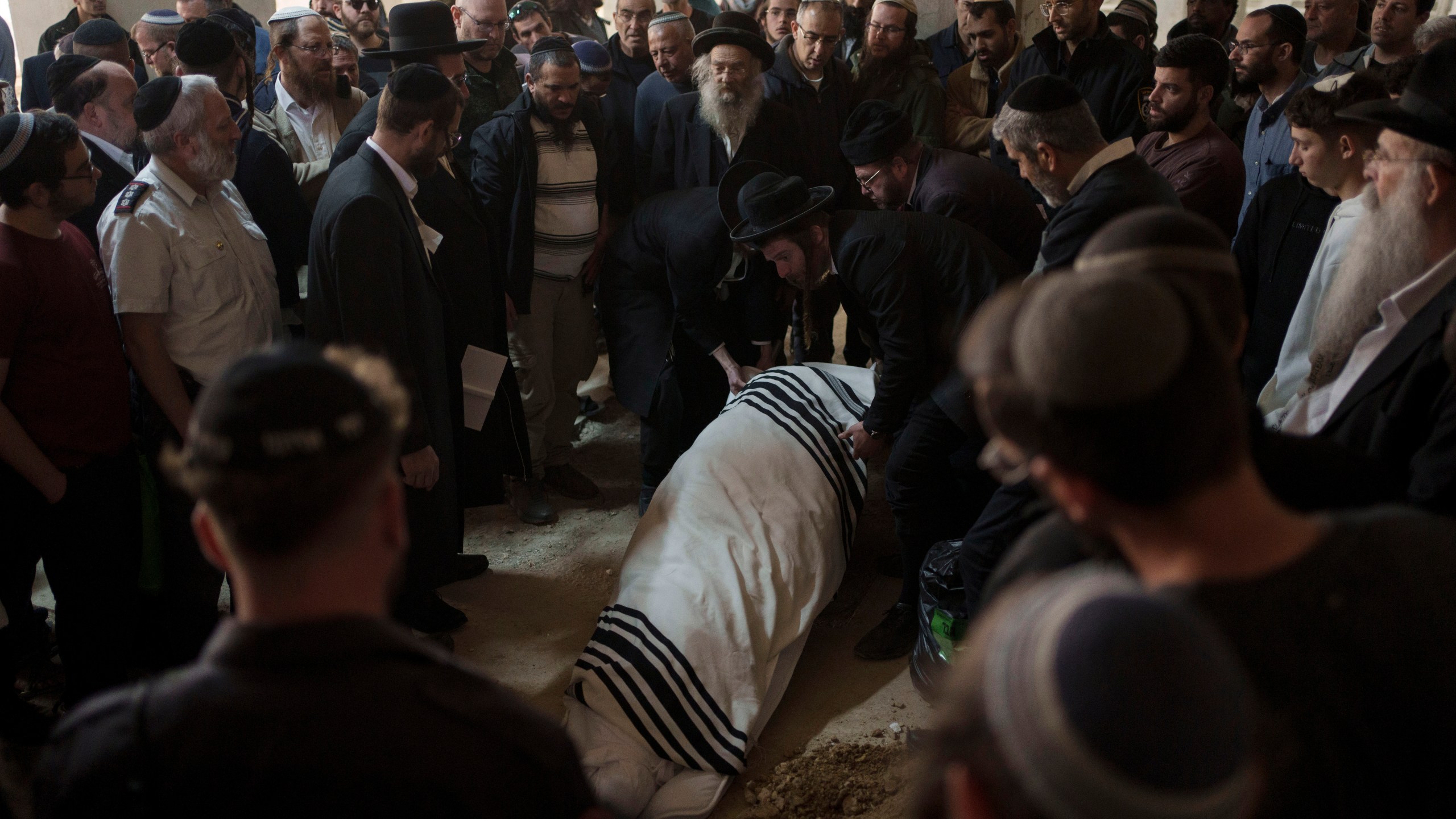 The body of Yitzhak Zeiger is placed in his grave during his funeral at a cemetery in Jerusalem, Israel, Friday, March 1, 2024. Two Israelis, including Zeiger, were killed in a Palestinian shooting attack at a gas station near the Jewish settlement of Eli, in the occupied West Bank on Thursday, the Israeli military said. (AP Photo/Leo Correa)