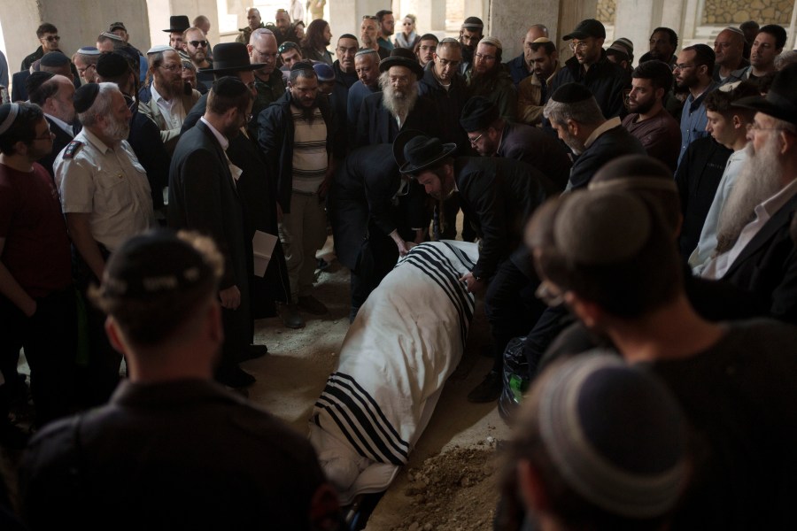 The body of Yitzhak Zeiger is placed in his grave during his funeral at a cemetery in Jerusalem, Israel, Friday, March 1, 2024. Two Israelis, including Zeiger, were killed in a Palestinian shooting attack at a gas station near the Jewish settlement of Eli, in the occupied West Bank on Thursday, the Israeli military said. (AP Photo/Leo Correa)