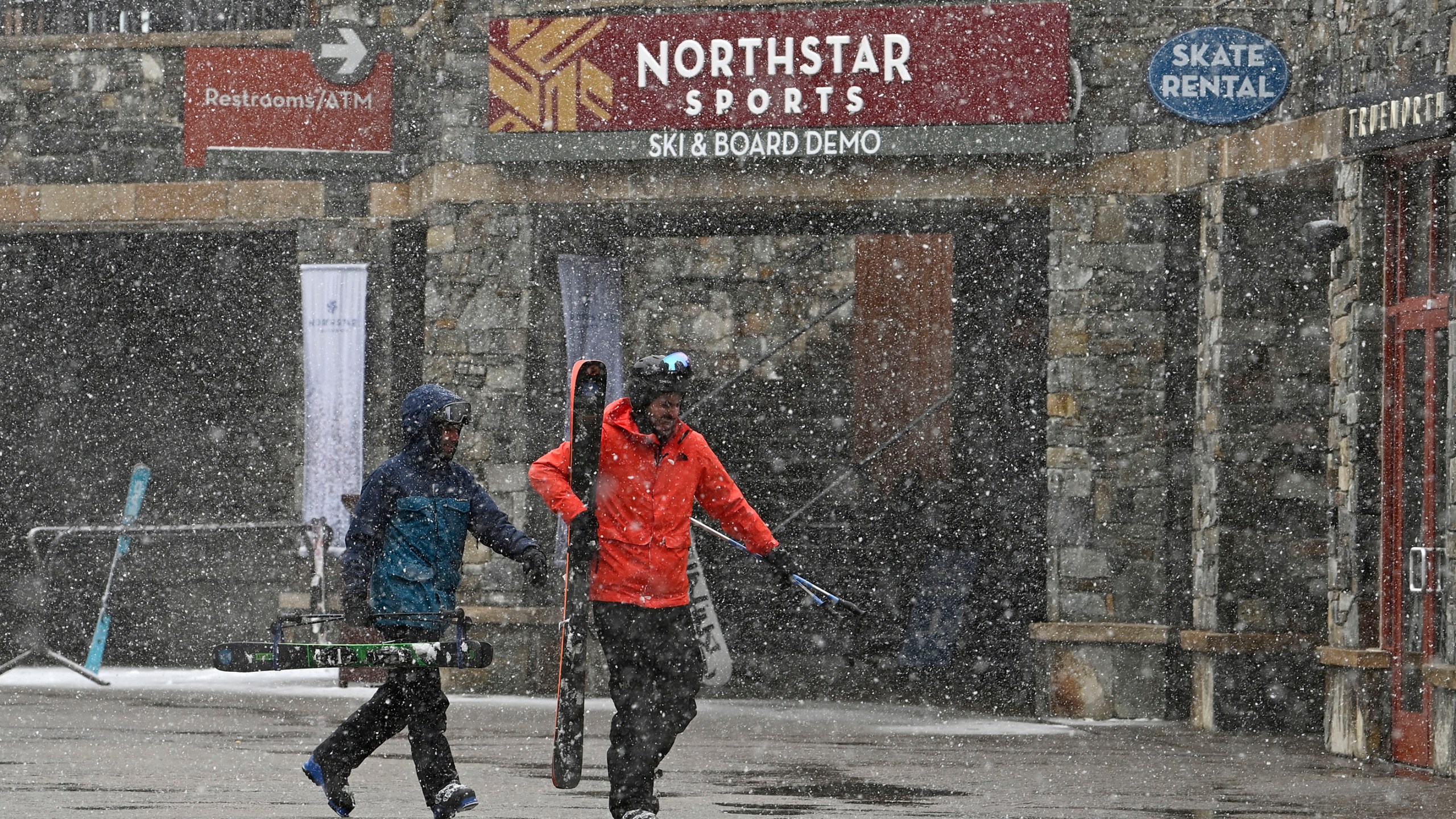 Skiers hurry along The Village at Northstar California Resort as snow falls on Thursday, Feb. 29, 2024, in Truckee, Calif. The most powerful Pacific storm of the season started barreling into the Sierra Nevada on Thursday, packing multiple feet of snow and dangerous winds that forecasters say will create blizzard conditions likely to close major highways and trigger power outages into the weekend.(AP Photo/Andy Barron)