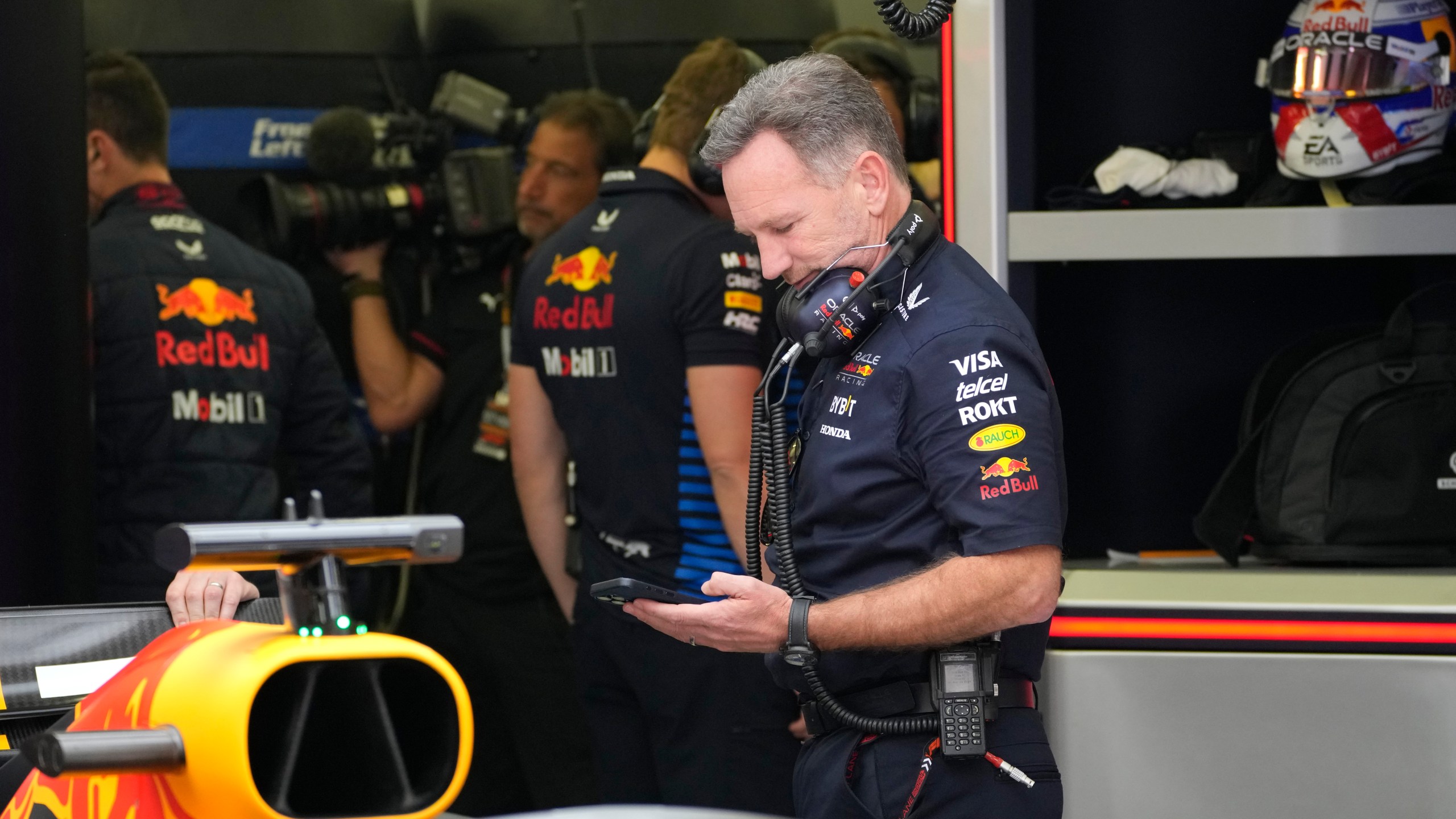 Red Bull team principal Christian Horner looks at a mobile phone as he stands in his team garage during the third practice session ahead of the Formula One Bahrain Grand Prix at the Bahrain International Circuit in Sakhir, Bahrain, Friday, March 1, 2024. (AP Photo/Darko Bandic)