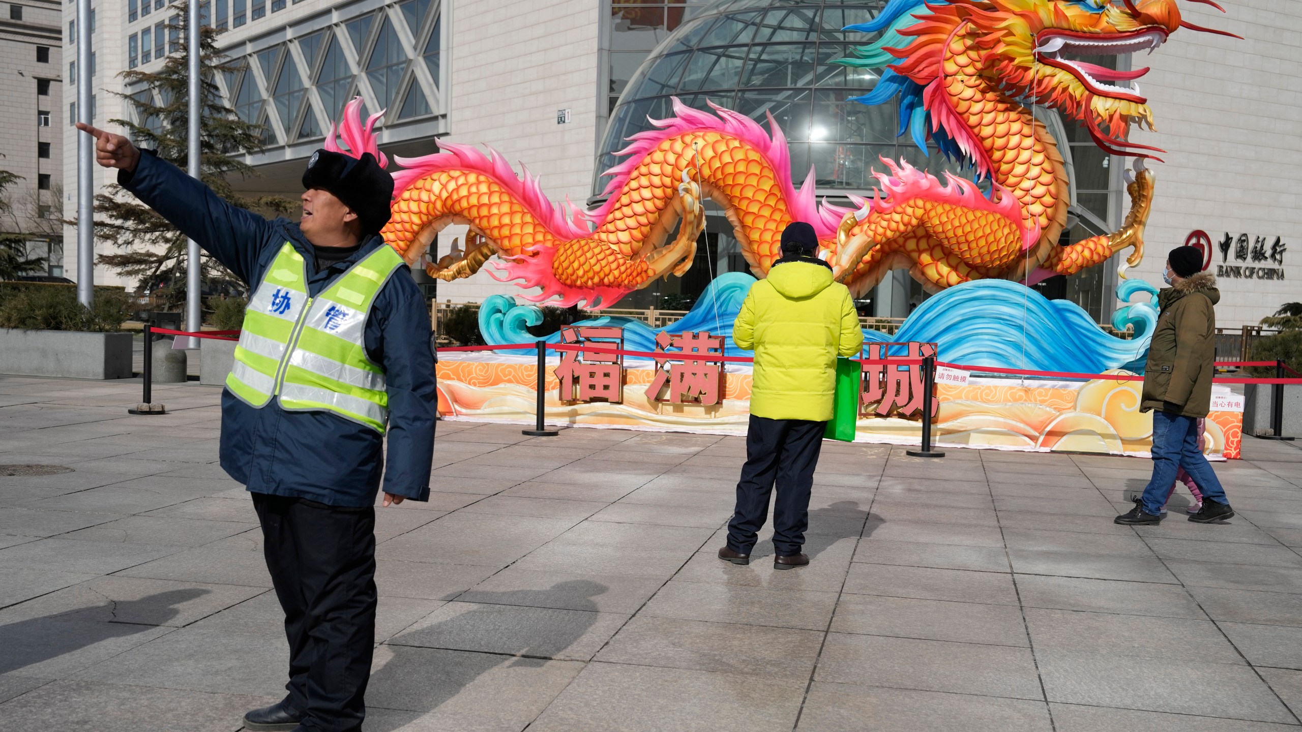 A municipal worker gives direction near a sculpture of a dragon in Beijing, Saturday, March 2, 2024. One burning issue dominates as the 2024 session of China's legislature gets underway this week: the economy. The National People's Congress annual meeting, which opens Tuesday, is being closely watched for any signals on what the ruling Communist Party might do to re-energize an economy that is sagging under the weight of expanded government controls and the bursting of a real-estate bubble. (AP Photo/Ng Han Guan)