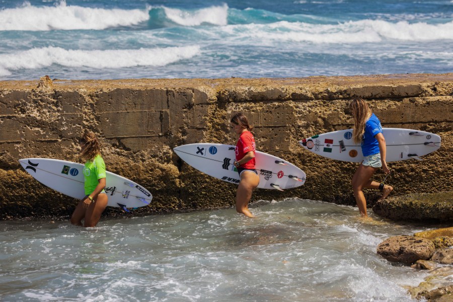 Surfers enter the water to compete in the ISA World Surfing Games, a qualifier for the Paris 2024 Olympic Games, on La Marginal beach in Arecibo, Puerto Rico, Wednesday, Feb. 28, 2024. (AP Photo/Alejandro Granadillo)