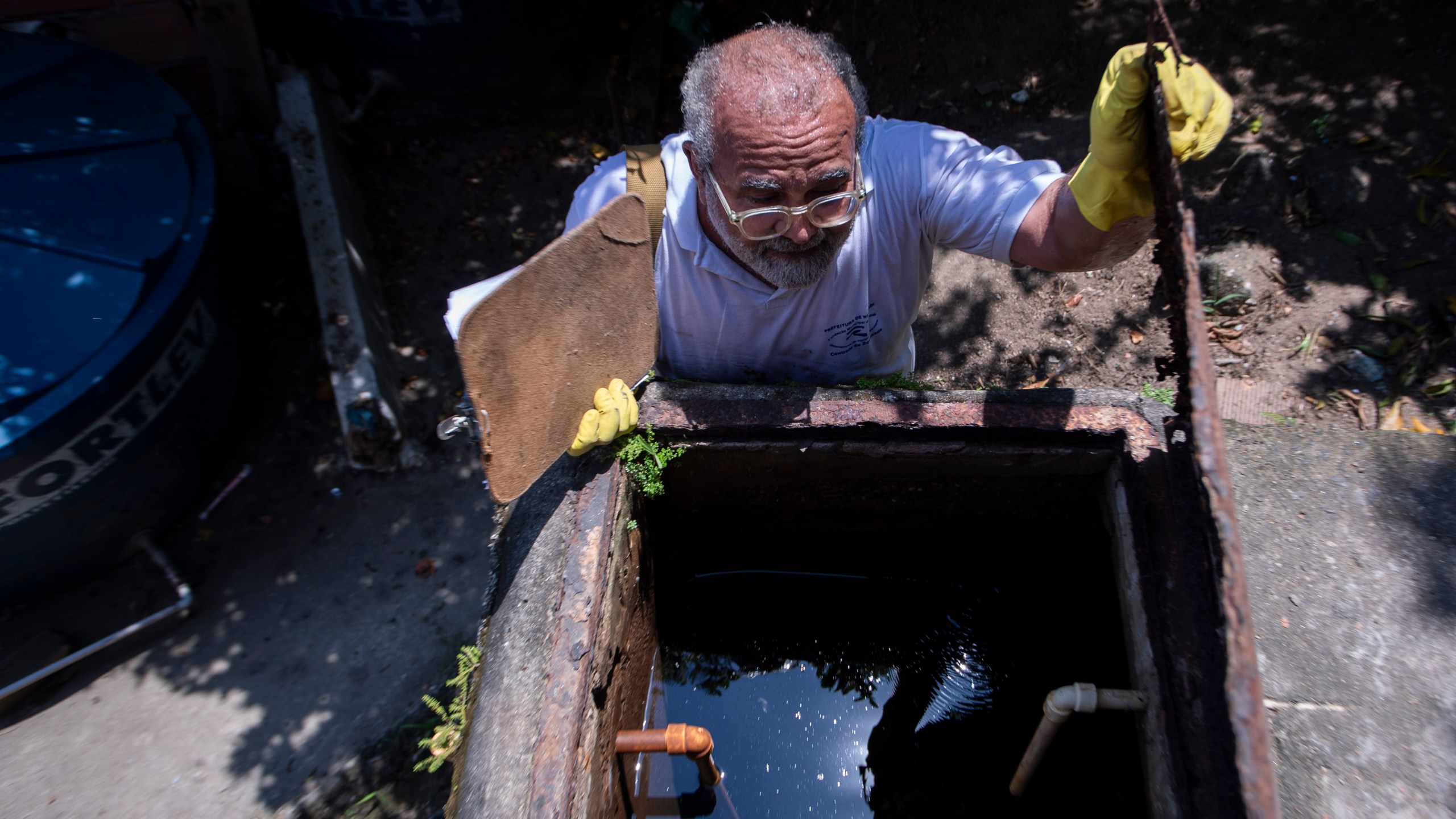 Augusto Cesar, a city worker who combats endemic diseases, inspects a water tank where mosquitoes can breed to eradicate the Aedes aegypti mosquito which can spread dengue in the Morro da Penha favela of Niteroi, Brazil, Friday, March 1, 2024. (AP Photo/Bruna Prado)