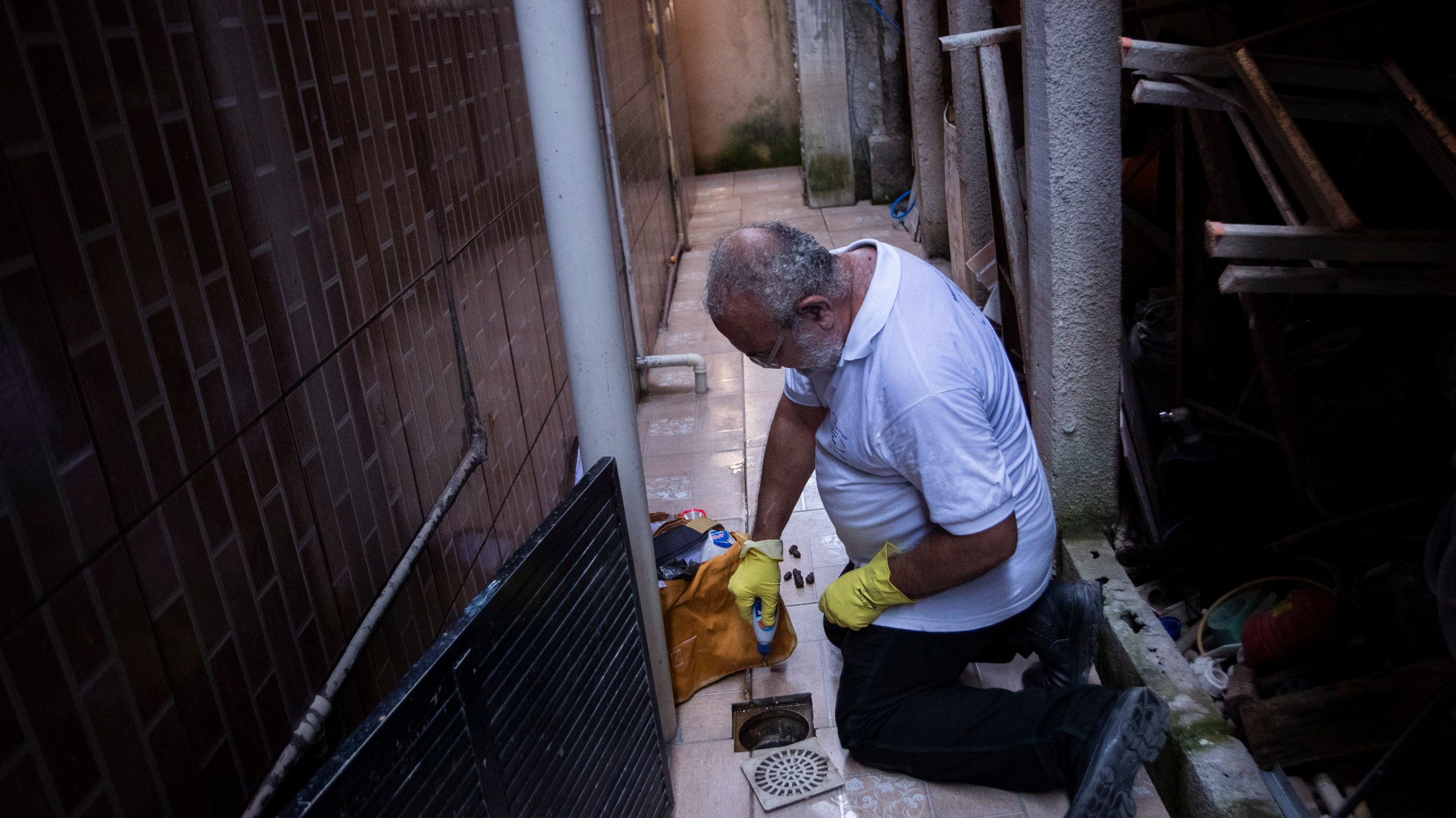 Augusto Cesar, a city worker who combats endemic diseases, pours larvicide down a home's drain where mosquitoes can breed, to help eradicate the Aedes aegypti mosquito which can spread dengue, in the Morro da Penha favela of Niteroi, Brazil, Friday, March 1, 2024. (AP Photo/Bruna Prado)