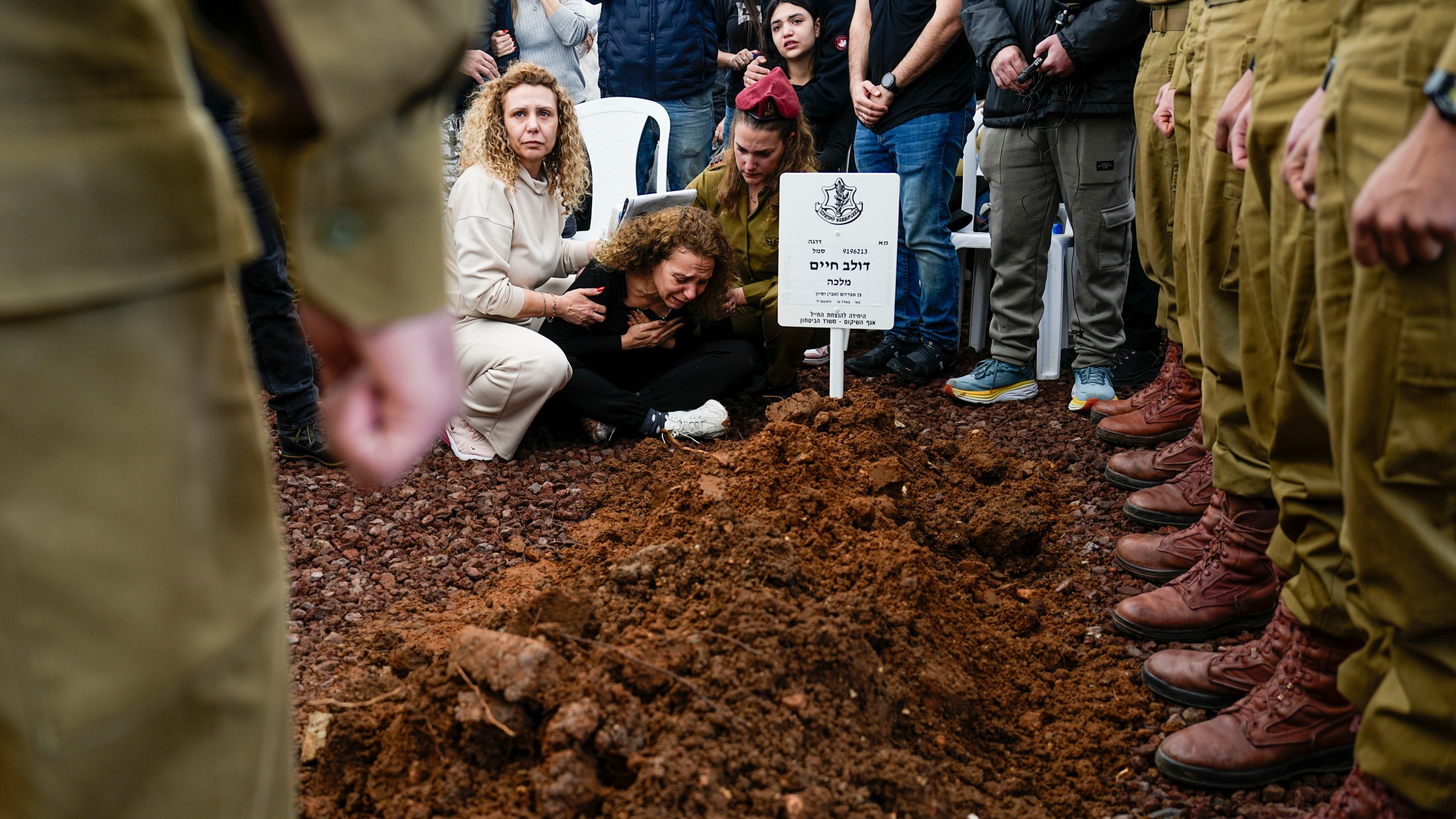 Sivan, mother of Israeli soldier, Sergeant Dolev Malca mourns in grief over his grave during his funeral in Shlomi, northern Israel, on the border with Lebanon, Sunday, March 3, 2024. Malca ,19, was killed during Israel's ground operation in the Gaza Strip, where the Israeli army has been battling Palestinian militants in the war ignited by Hamas' Oct. 7 attack into Israel. (AP Photo/Ariel Schalit)
