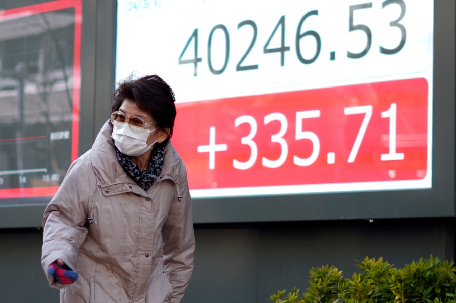 A person walks in front of an electronic stock board showing Japan's Nikkei 225 index at a securities firm Monday, March 4, 2024, in Tokyo. Japan's Nikkei 225 share benchmark has topped 40,000 for the first time as strong demand for technology shares keeps pushing the index higher.(AP Photo/Eugene Hoshiko)