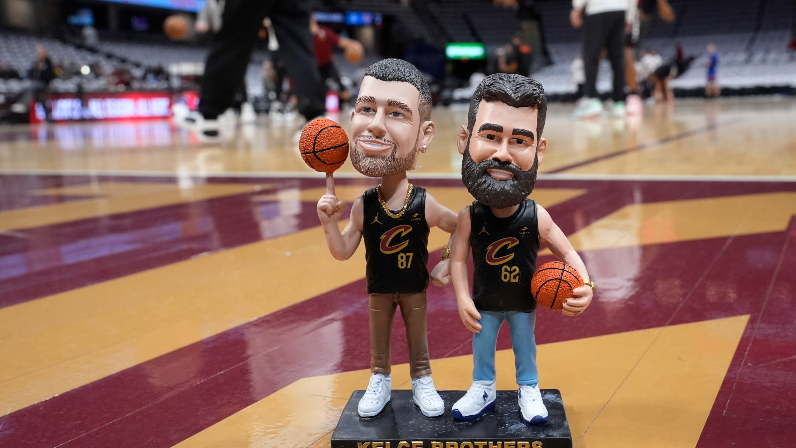 A bobblehead of Cleveland natives Travis and Jason Kelce stands on the Cleveland Cavaliers' court Sunday, March 3, 2024, in Cleveland. The team will give the bobbleheads to fans at an NBA basketball game against the Boston Celtics, Tuesday, March 5. (AP Photo/Sue Ogrocki)
