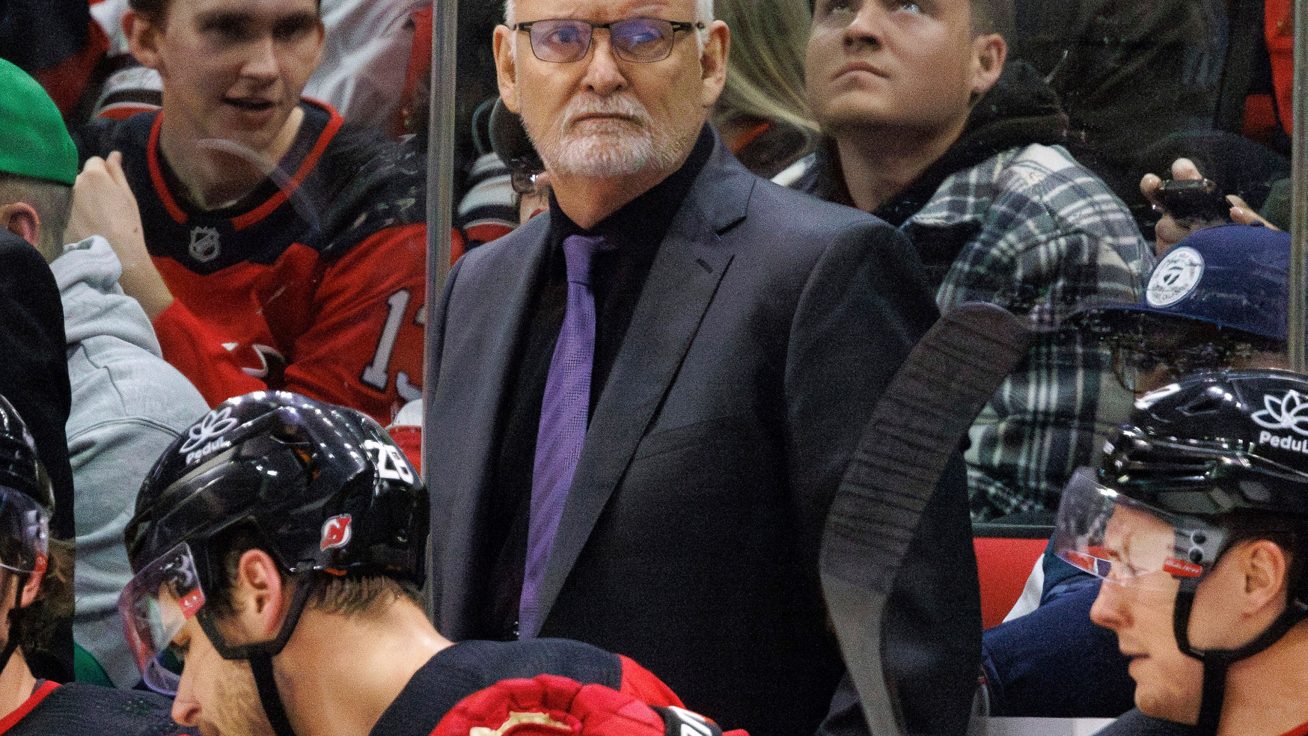 FILE - New Jersey Devils head coach Lindy Ruff, center, looks toward the ice during the third period of an NHL hockey game against the Carolina Hurricanes in Raleigh, N.C., Feb. 10, 2024. The Devils have fired Ruff. Assistant Travis Green has been named as the interim replacement. General manager Tom Fitzgerald made the stunning move with less than 30 games left in the NHL season. (AP Photo/Ben McKeown, File)