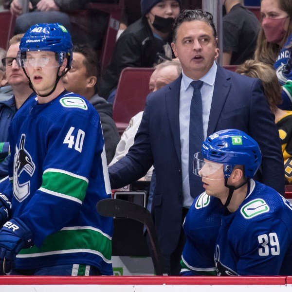 FILE - Vancouver Canucks coach Travis Green, upper right, stands on the bench behind Elias Pettersson (40) and Alex Chiasson (39) during the third period of an NHL hockey game against the Pittsburgh Penguins, Dec. 4, 2021, in Vancouver, British Columbia. The New Jersey Devils have fired coach Lindy Ruff. Current Devils assistant Green has been named as the interim replacement. General manager Tom Fitzgerald made the stunning move with less than 30 games left in the NHL season. (Darryl Dyck/The Canadian Press via AP, File)