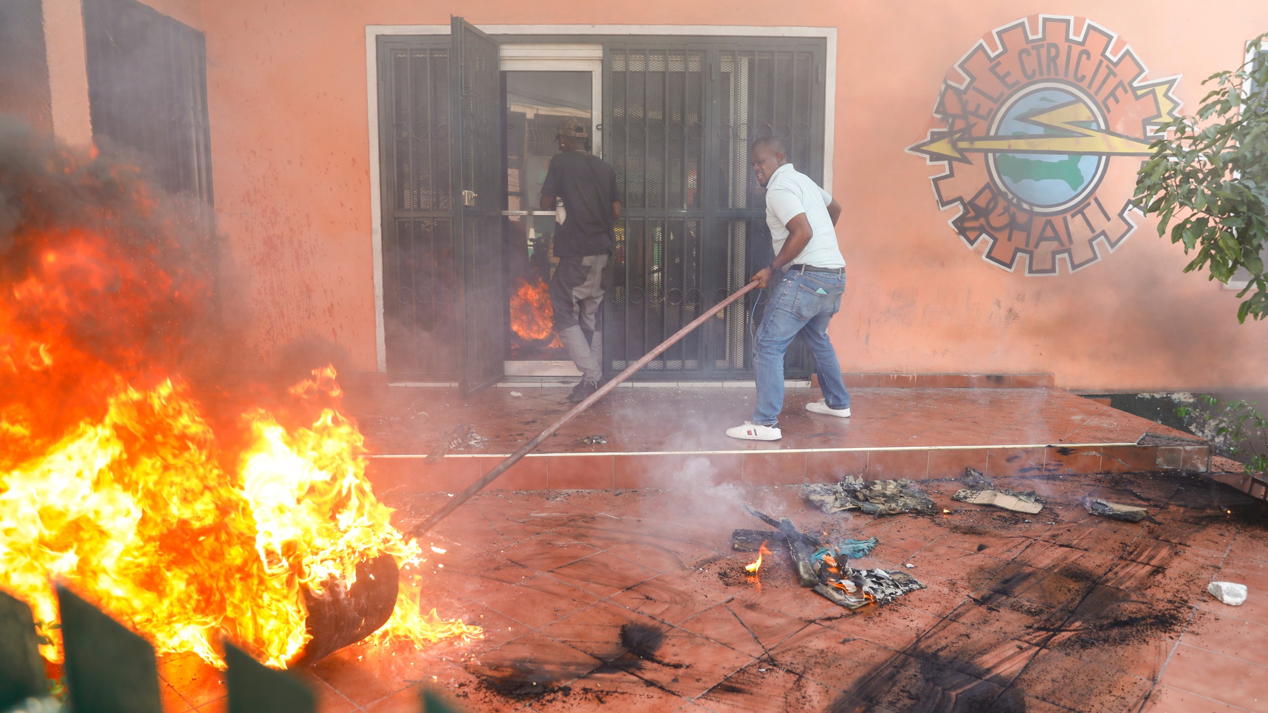 Workers put down a fire set at an office of Haiti's power company during a protest to demand the resignation of the Prime Minister Ariel Henry in Port-au-Prince, Haiti, Friday, March 1, 2024. (AP Photo/Odelyn Joseph)