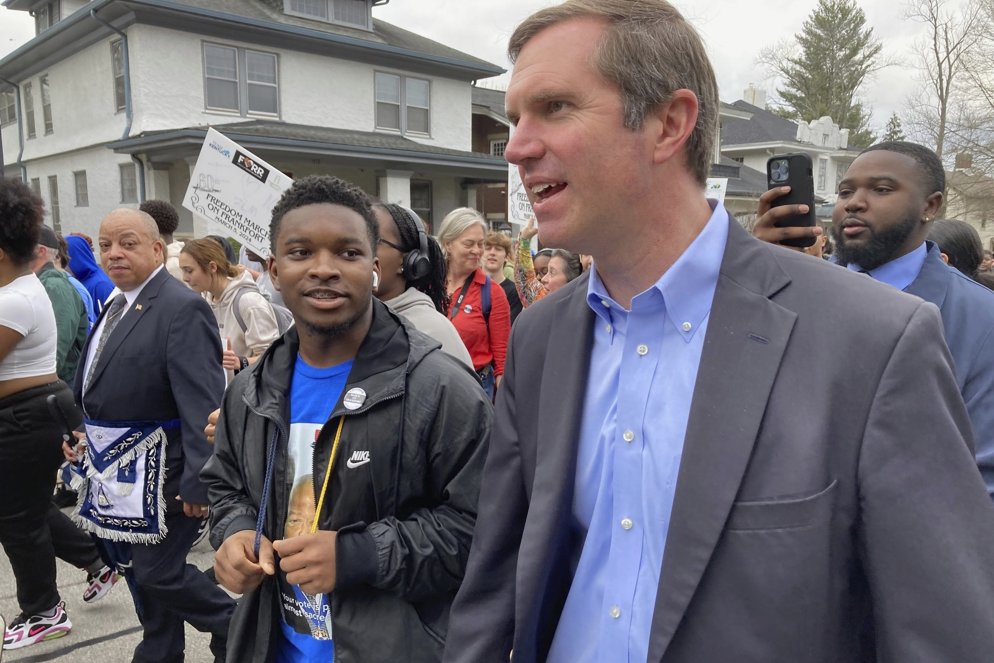 Kentucky Gov. Andy Beshear, right, chats with a student as they march, Tuesday, March 5, 2024, in Frankfort, Ky. They joined others to commemorate a landmark civil rights event known as the 1964 March on Frankfort. (AP Photo/Bruce Schreiner)
