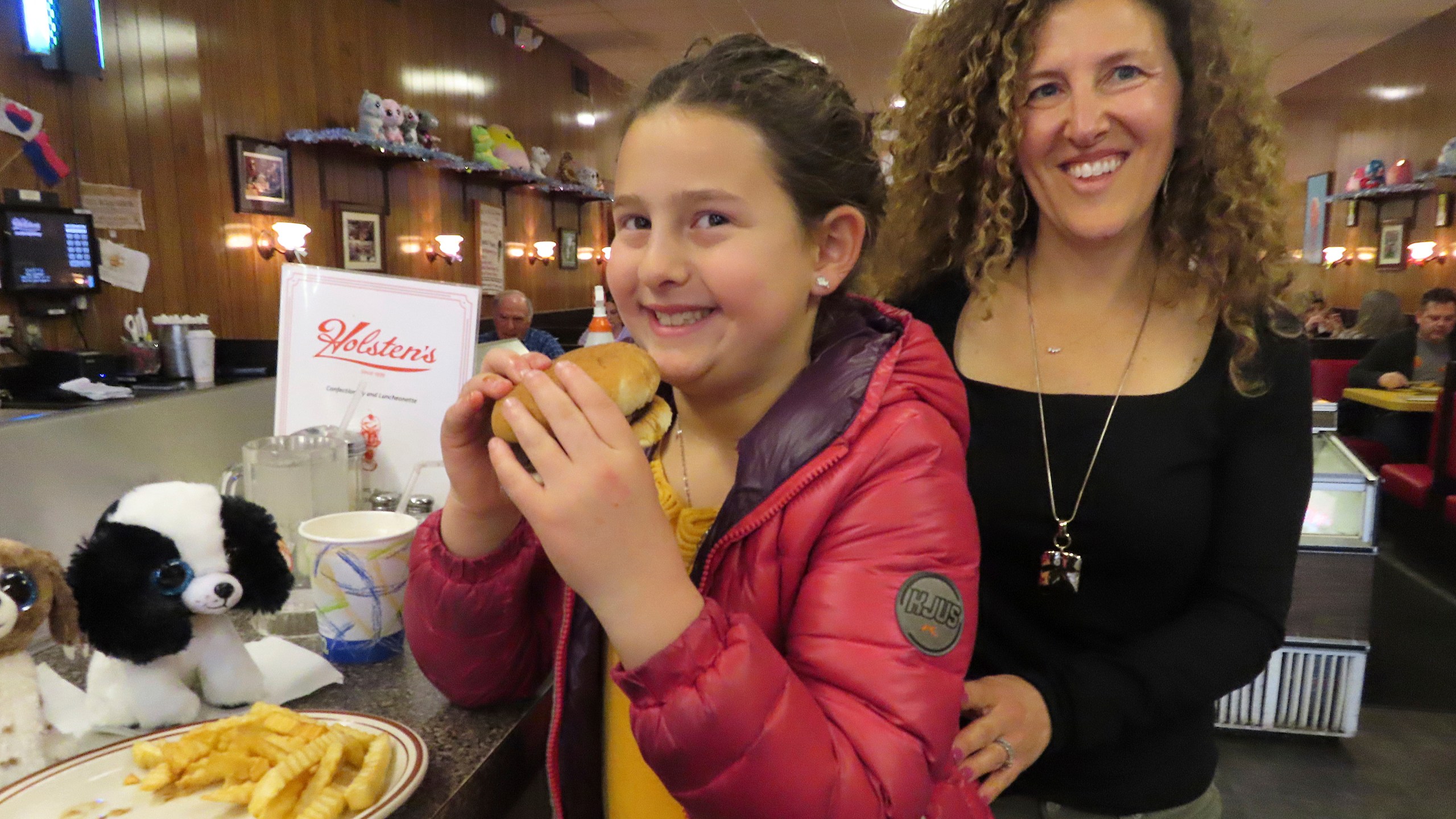 Evie Polera, left, and her mother Dara Polera, right, eat on March 5, 2024, at the counter of Holsten's, the Bloomfield N.J. ice cream parlor and restaurant where the final scene of "The Sopranos" TV series was filmed. A day earlier, the booth where Tony Soprano may or may not have met his end was sold in an online auction for $82,600 to a buyer that wishes to remain anonymous. (AP Photo/Wayne Parry)