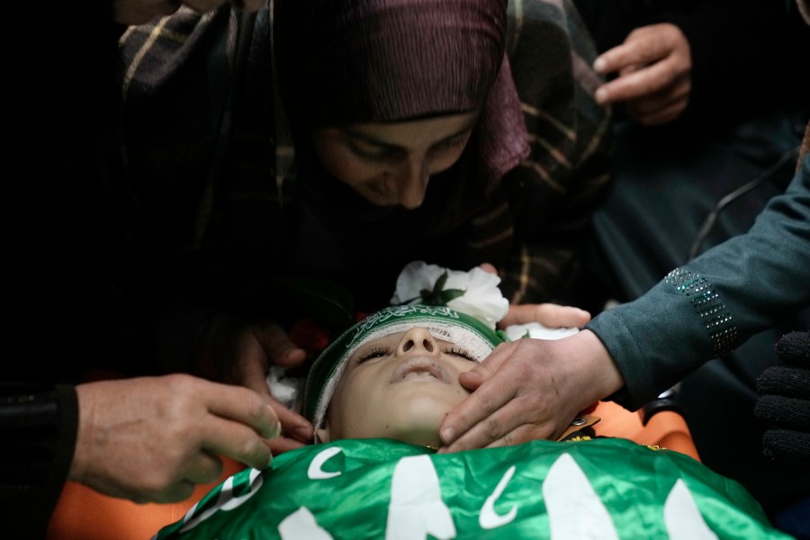 The mother of Amr al-Najjar, 11, draped in the Hamas flag, center, weeps during his funeral in the West Bank village of Burin, near Nablus, Tuesday, March 5, 2024. Palestinian media reports that he was shot during an Israeli military incursion into the village of Burin. The Israeli military says they opened fire in the village and are aware of reports of a minor being killed. (AP Photo/Majdi Mohammed)