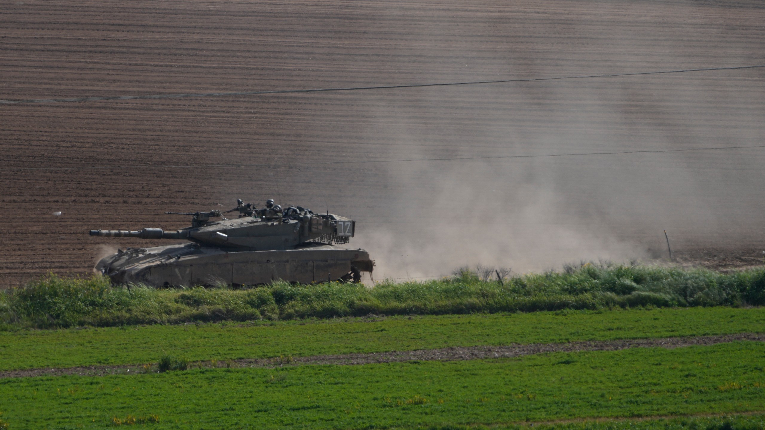 Israeli soldiers move on the top of a tank near the Israeli-Gaza border as seen from southern Israel, Wednesday, March 6, 2024. (AP Photo/Ohad Zwigenberg)