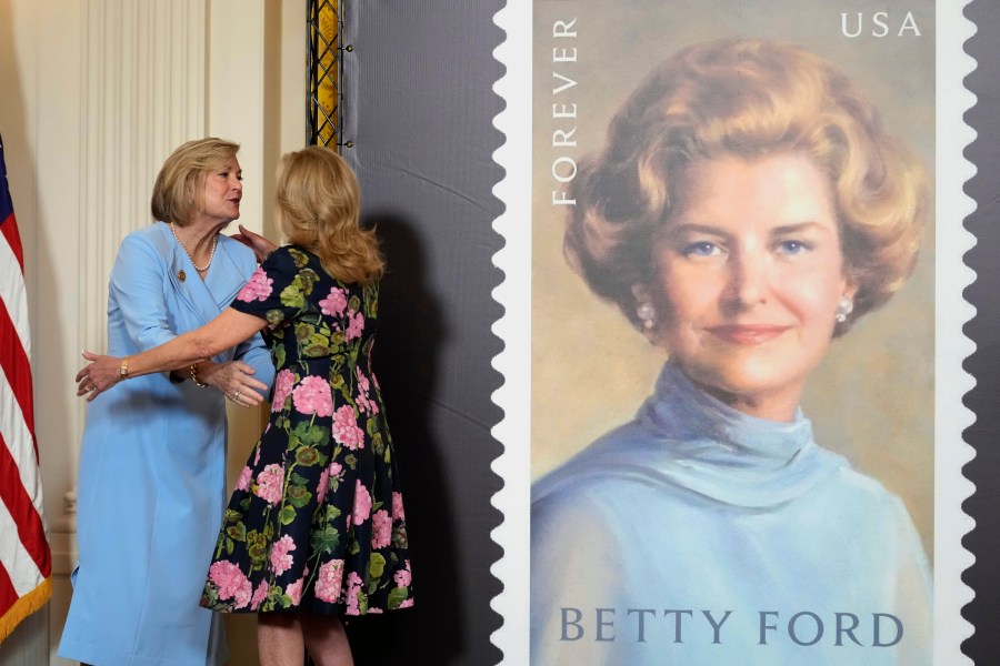 First lady Jill Biden, right, and Susan Ford Bales, left, daughter of former first lady Betty Ford, hug in the East Room of the White House in Washington, Wednesday, March 6, 2024, during an unveiling of a new U.S. Postal Service stamp honoring former first lady Betty Ford. (AP Photo/Susan Walsh)