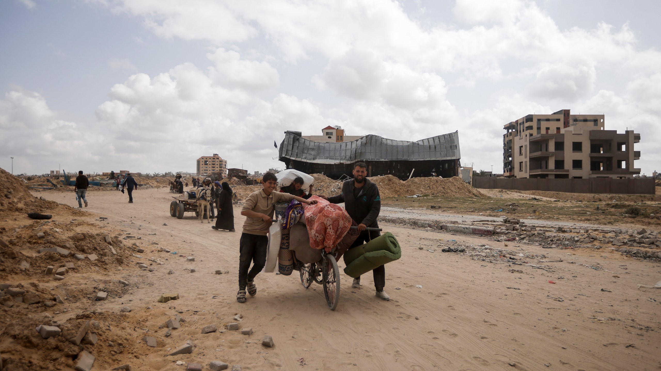 Palestinians carry their belonging after visiting their houses destroyed in the Israeli offensive on Khan Younis, Gaza Strip, Wednesday, March 6, 2024. (AP Photo/Mohammed Dahman)