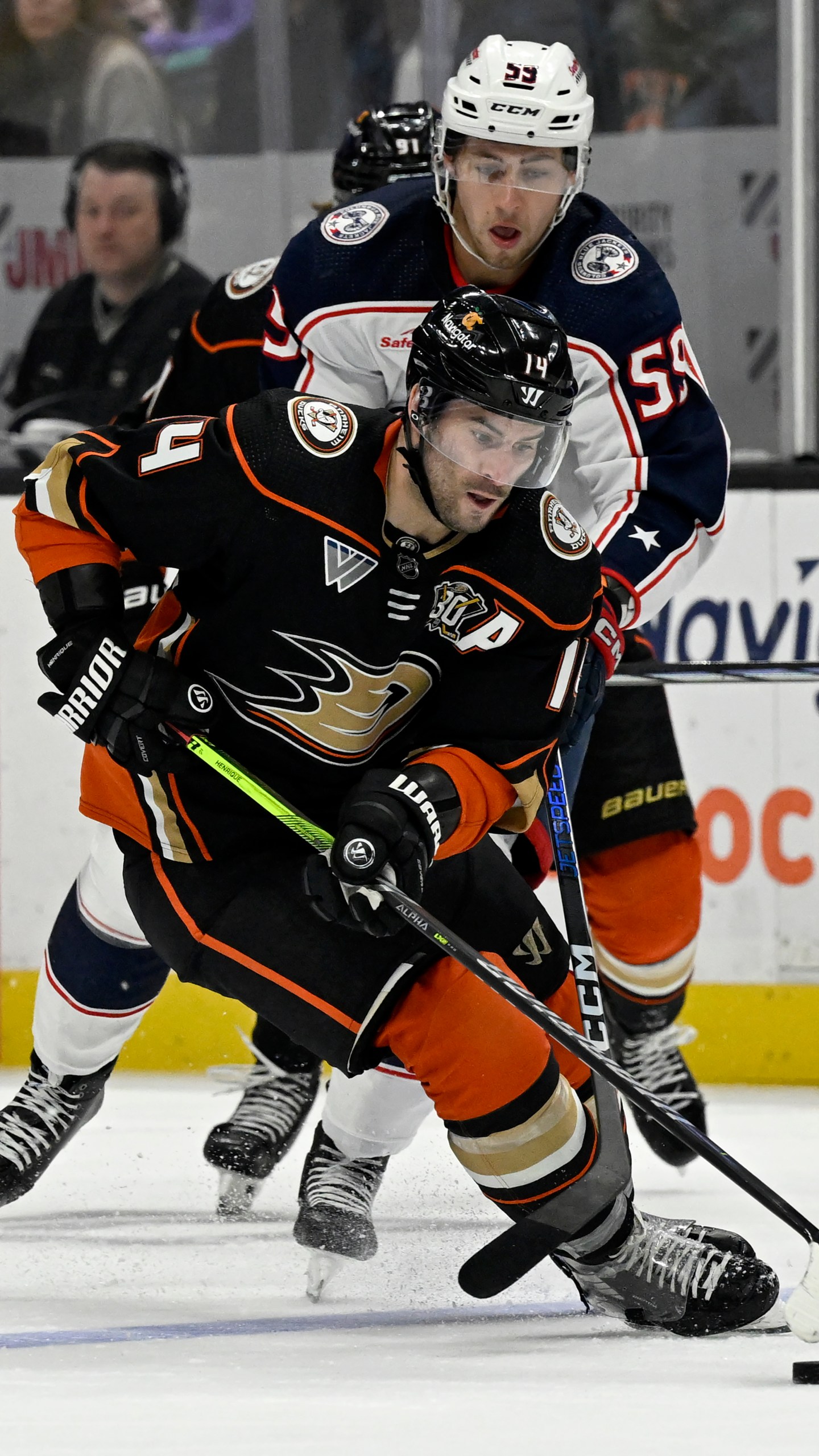 Anaheim Ducks center Adam Henrique (14) controls the puck past Columbus Blue Jackets right wing Yegor Chinakhov (59) during the second period of an NHL hockey game in Anaheim, Calif., Wednesday, Feb. 21, 2024. (AP Photo/Alex Gallardo)