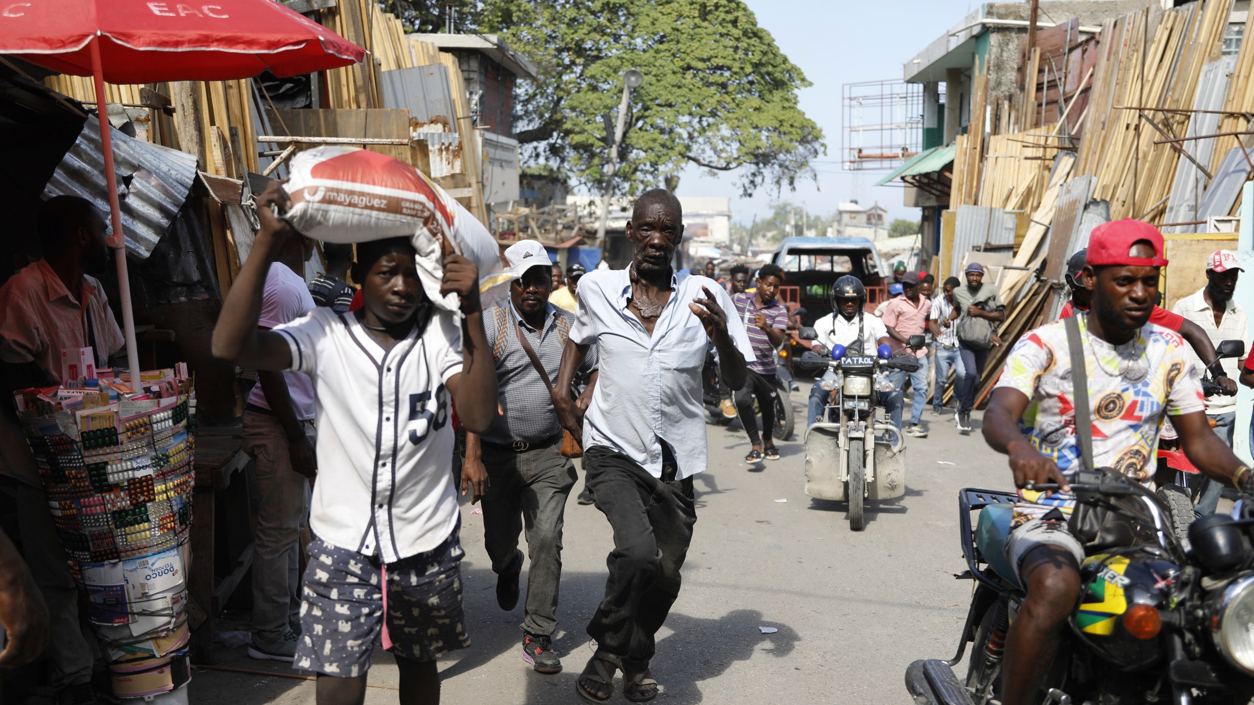 Pedestrians run for cover after hearing gunshots in Port-au-Prince, Haiti, Thursday, March 7, 2024. (AP Photo/Odelyn Joseph)