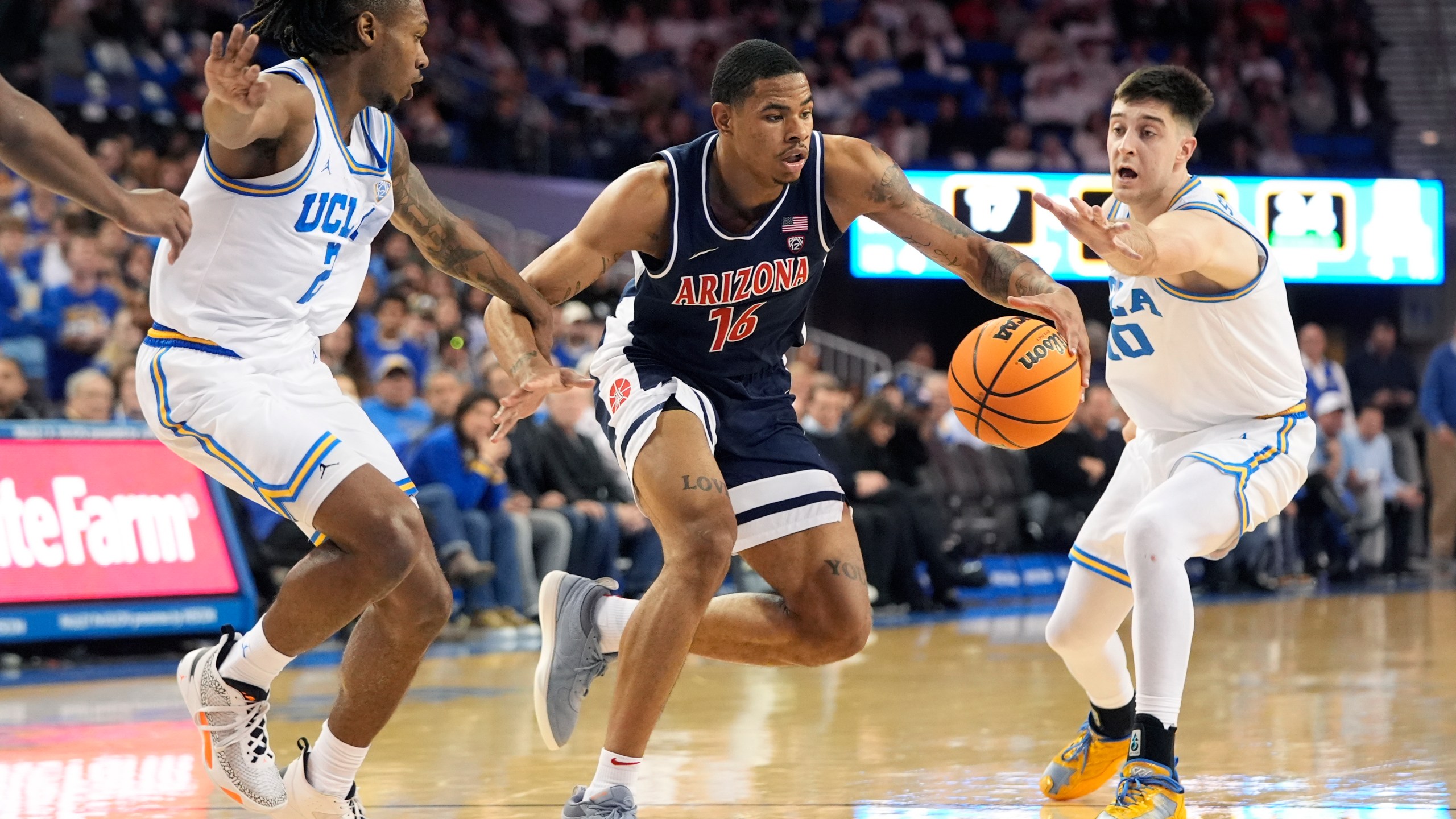 Arizona's Keshad Johnson (16) dribbles under pressure by UCLA guard Dylan Andrews (2) and Lazar Stefanovic (10) during the first half of an NCAA college basketball game in Los Angeles, Thursday, March 7, 2024. (AP Photo/Jae C. Hong)