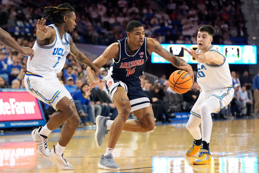 Arizona's Keshad Johnson (16) dribbles under pressure by UCLA guard Dylan Andrews (2) and Lazar Stefanovic (10) during the first half of an NCAA college basketball game in Los Angeles, Thursday, March 7, 2024. (AP Photo/Jae C. Hong)