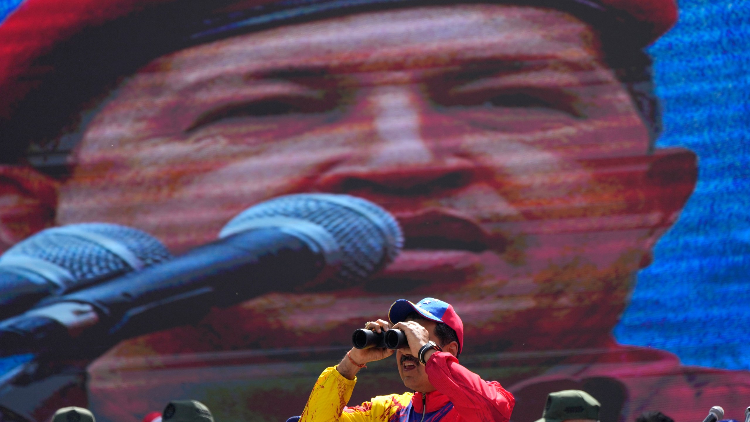 FILE - Venezuelan President Nicolas Maduro looks through a pair of binoculars while standing on the main stage during a commemorative event, in Caracas, Venezuela, Feb. 29, 2024. Maduro became Venezuela's interim president in March 2013 after the death of Hugo Chávez and elected a few months later. He is seeking his third six-year term in the upcoming presidential election. (AP Photo/Ariana Cubillos, File)