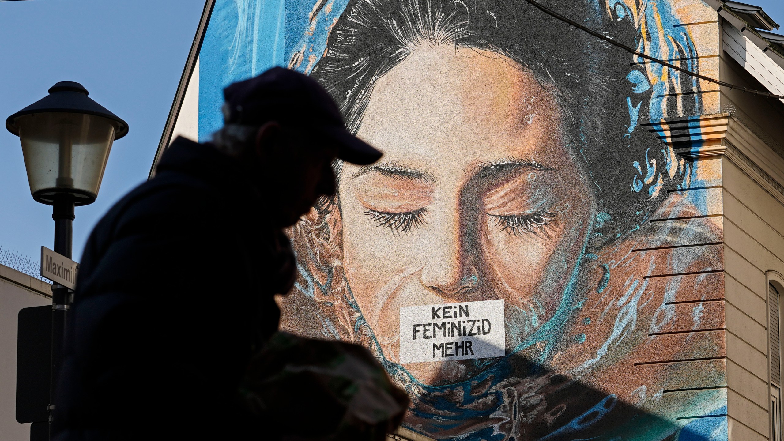 A man passes a large protest painting against hate crime against women, reading "no more femicide" at a house wall in Gelsenkirchen, Germany, on the International Women's Day, Friday, March 8, 2024. Marches, demonstrations and conferences are being held the world over, from Asia to Latin America and elsewhere to mark International Women’s Day. (AP Photo/Martin Meissner)