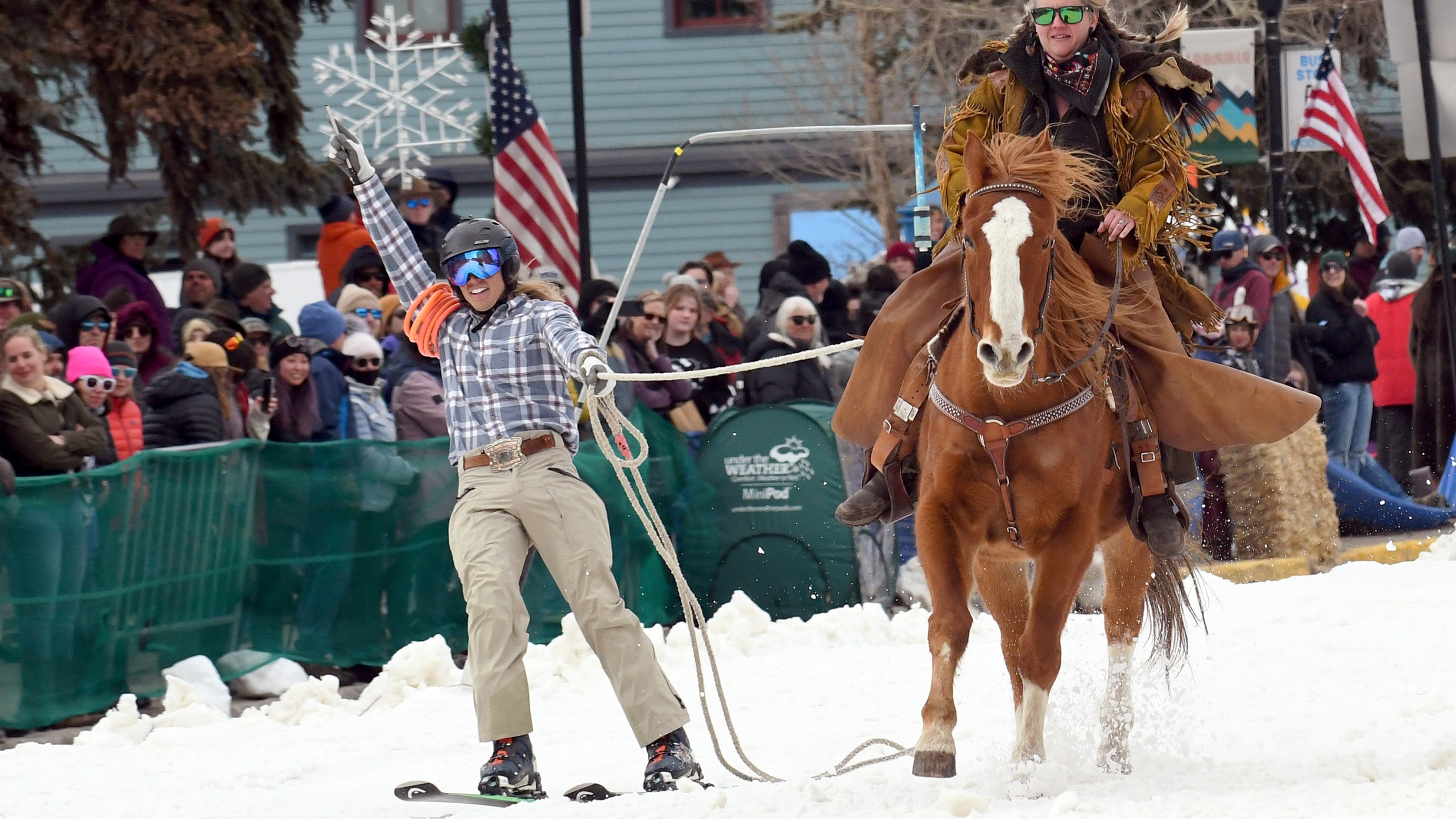 A skijoring team competes in Leadville, Colo., on Saturday, March 2, 2024. Skijoring draws its name from the Norwegian word skikjoring, meaning "ski driving." It started as a practical mode of transportation in Scandinavia and became popular in the Alps around 1900. Today's sport features horses at full gallop towing skiers by rope over jumps and around obstacles as they try to lance suspended hoops with a baton, typically a ski pole that's cut in half. (AP Photo/Thomas Peipert)
