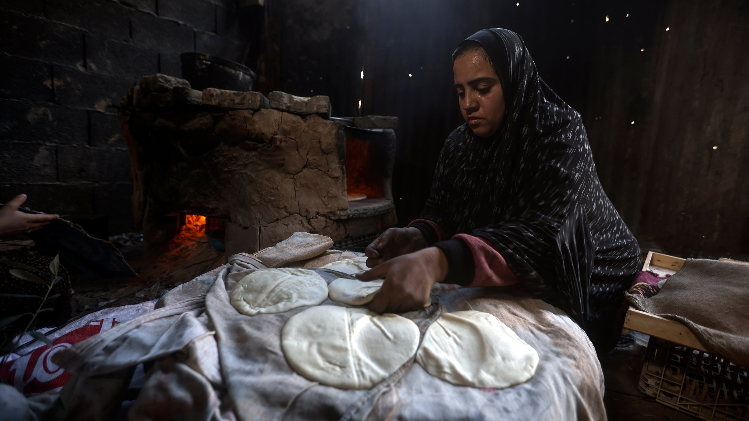 File - A Palestinian woman displaced by the Israeli ground offensive on the Gaza Strip bake bread at a makeshift tent camp in Rafah, Gaza Strip, Monday, Feb. 19, 2024. (AP Photo/Mohammed Dahman, File)