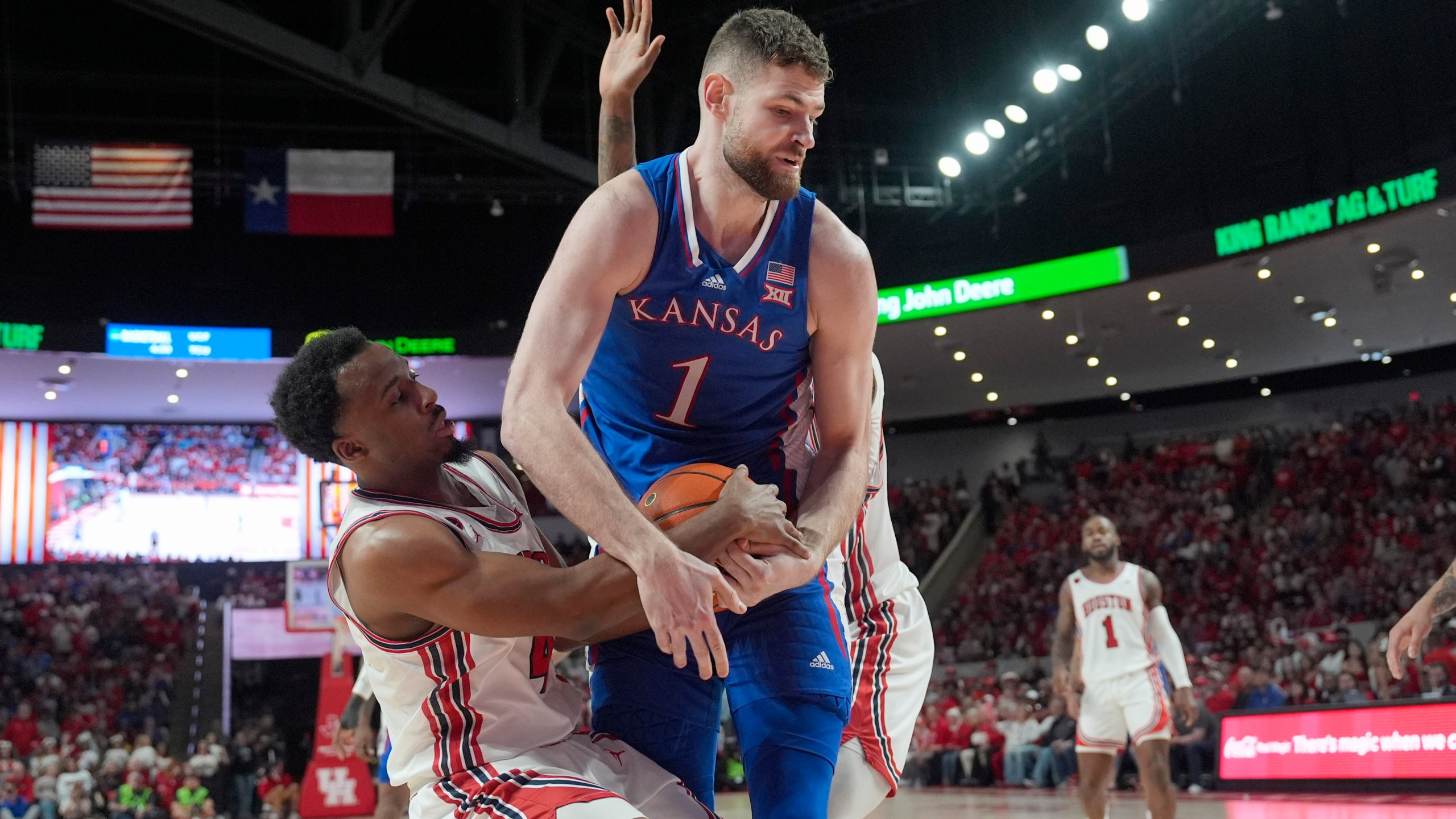 Houston's L.J. Cryer (4) reaches to steal the ball away from Kansas' Hunter Dickinson (1) during the first half of an NCAA college basketball game Saturday, March 9, 2024, in Houston. (AP Photo/David J. Phillip)