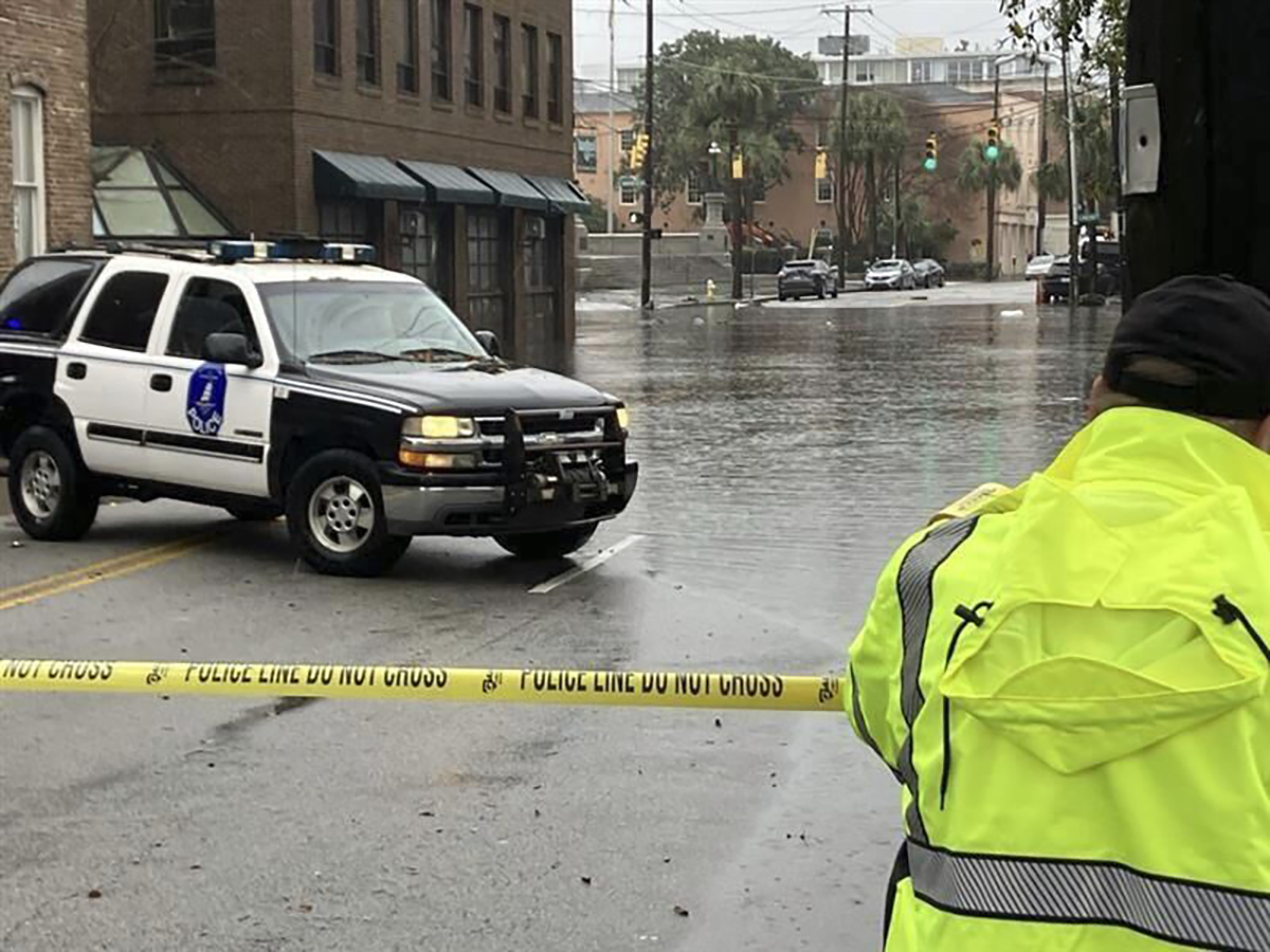 A Charleston police officer closes off a portion of Market Street during heavy rains and flooding on Saturday, March 9, 2024, in Charleston, S.C. (Glenn Smith/The Post And Courier via AP)