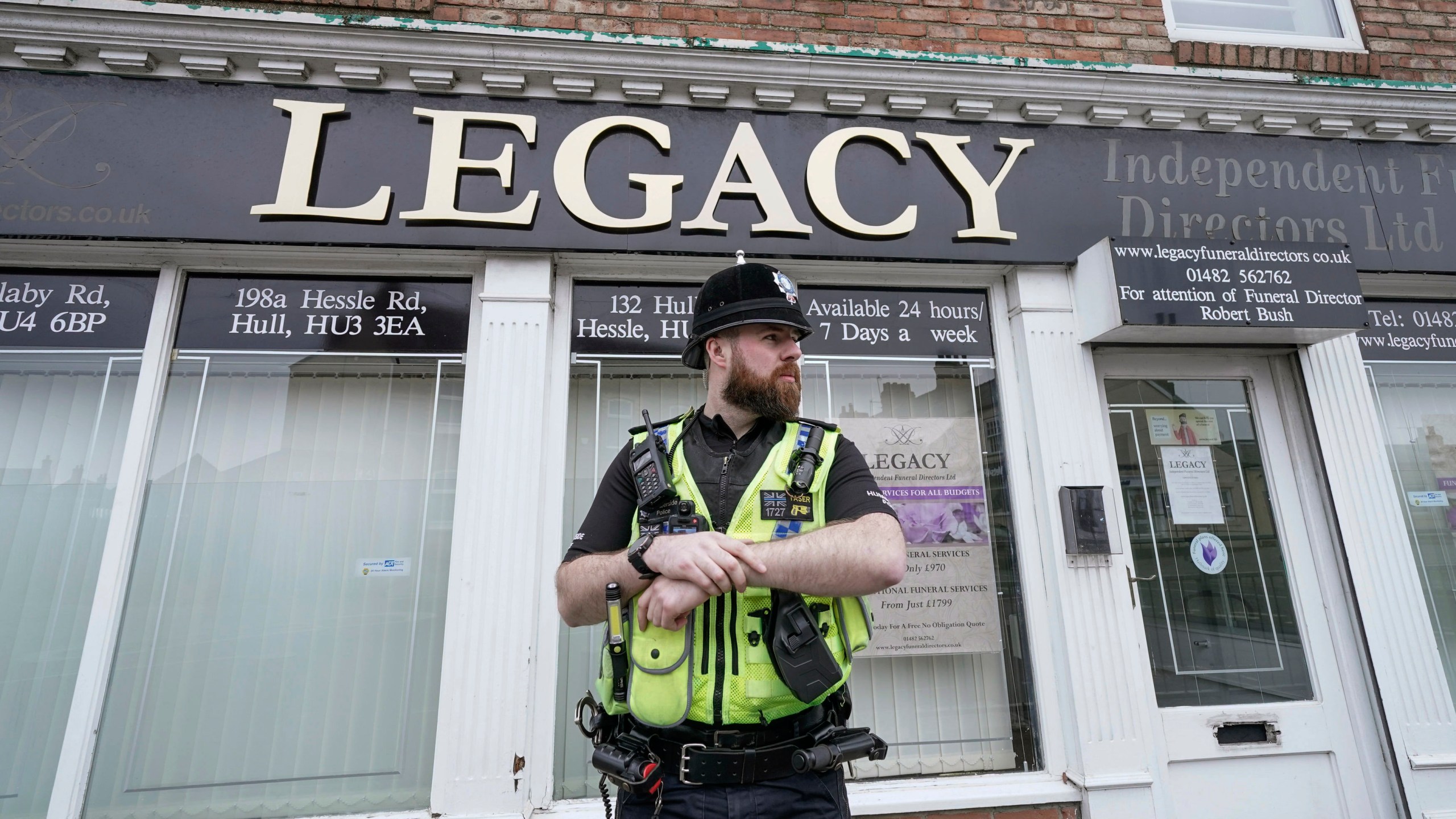Police stand guard outside the Beckside branch of Legacy Independent Funeral Directors, in Hull, England, Saturday, March 9, 2024. Police in northern England say they have removed 34 bodies from a funeral home and arrested a man and woman on suspicion of fraud and preventing lawful burials. The arrests Sunday follow several days of investigation at Legacy Funeral Directors in Hull and two related funeral homes. (Danny Lawson/PA via AP)