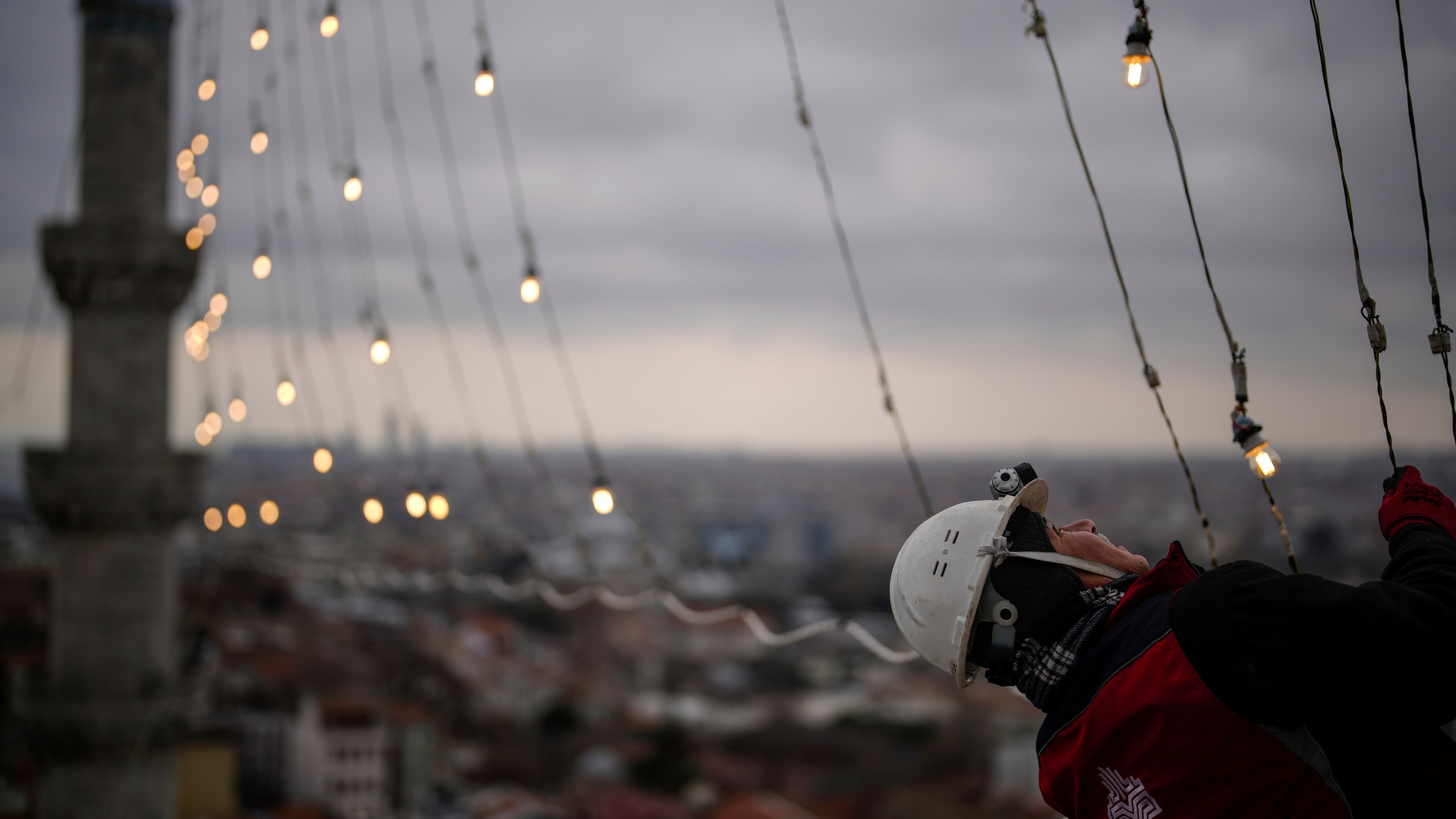 Mahya master Cemil Buyurkan works in the installation of a lights message at the top of one of the minarets of the Suleymaniye mosque ahead of the Muslim holy month of Ramadan, in Istanbul, Turkey, Wednesday, March 6, 2024. Mahya is the unique Turkish tradition of stringing religious messages and designs between minarets. (AP Photo/Emrah Gurel)