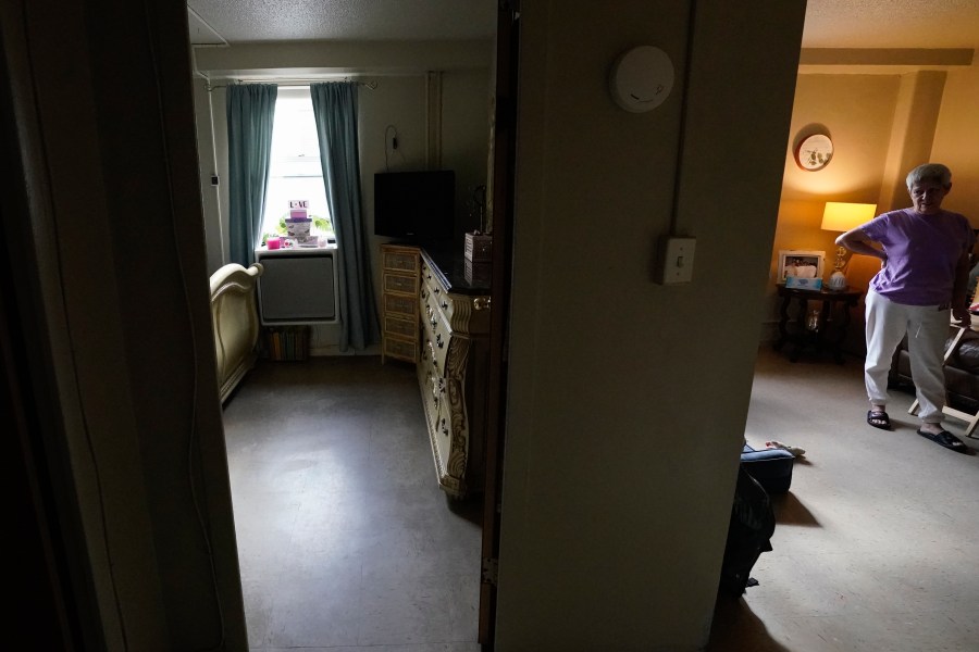 Regina Fred stands in her apartment as a window-mounted heat pump, left, in one of her bedrooms operates in the Queens borough of New York, on Thursday, Feb. 29, 2024. The heat pump, part of a pilot project by the New York City Housing Authority, is aimed at cutting energy costs and lowering emissions. (AP Photo)