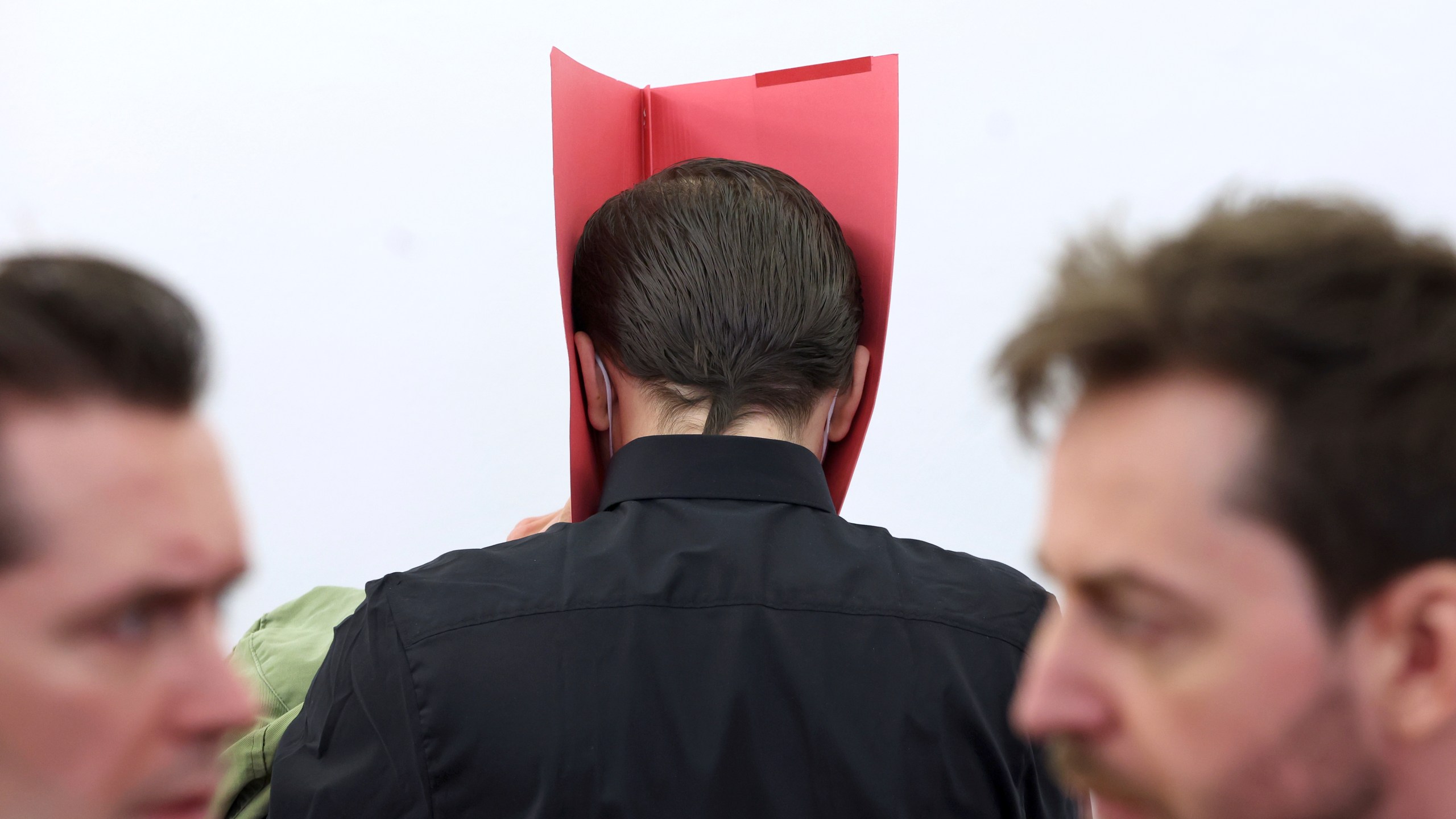 A 31-year-old American man accused of murder, center, stands in the dock between his lawyers Philip M'ller, left, and Alexander Stevens at the regional court in Kempten, Germany, Monday March 11, 2024. An American man was convicted of murder and other charges on Monday for brutally attacking two American women at a tourist site in southern Germany last summer and pushing them into a ravine, fatally injuring one of them. He was sentenced to life in prison. (Karl-Josef Hildenbrand/dpa via AP)