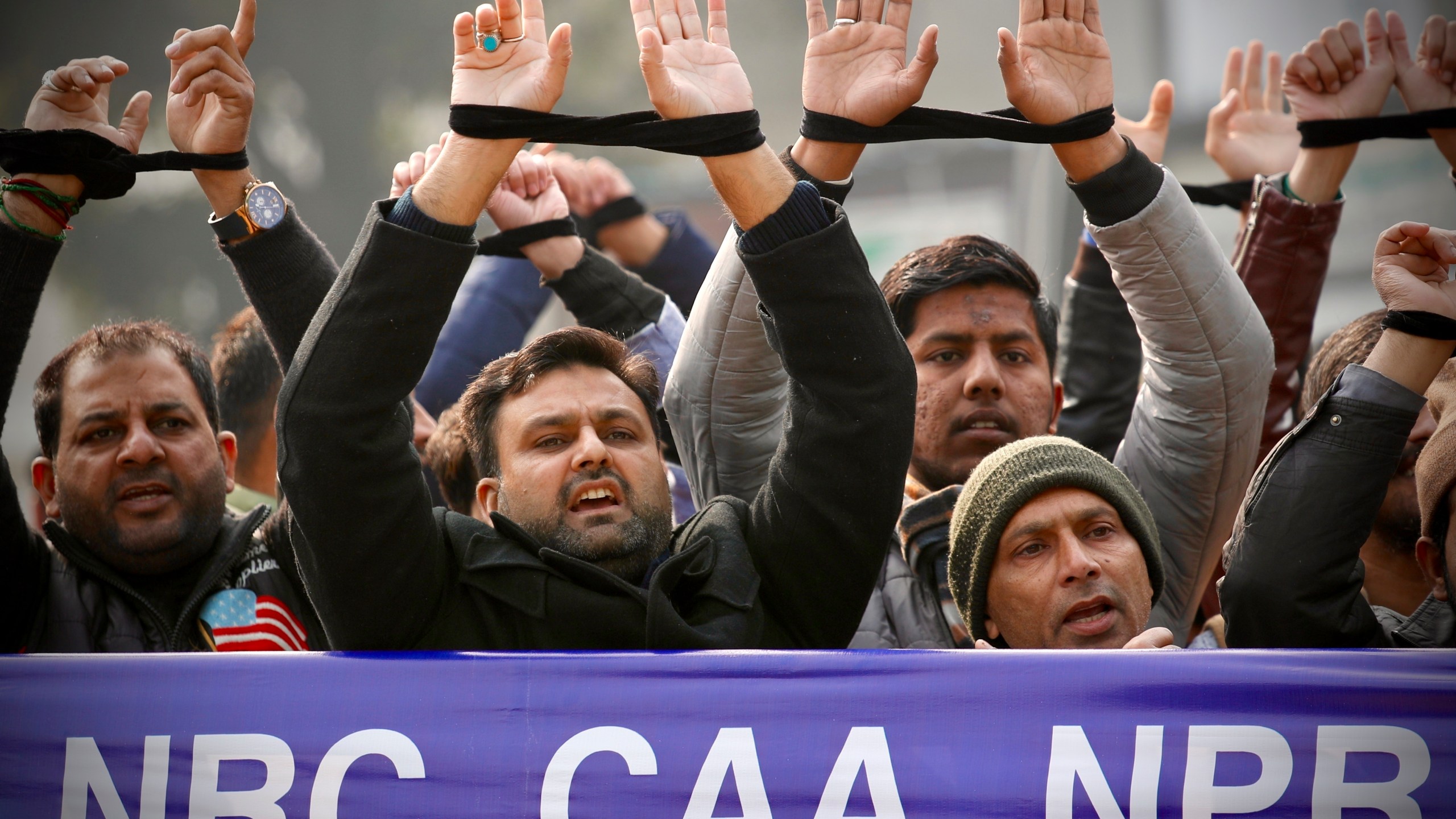 FILE- Indians raise their tied hands and shout slogans during a protest against the Citizenship Amendment Act in New Delhi, India, Dec. 27, 2019. Prime Minister Narendra Modi's government on Monday announced rules to implement a 2019 citizenship law that critics say is discriminatory against Muslims, weeks before the Hindu nationalist leader will seek a third term in office. (AP Photo/Manish Swarup, File)