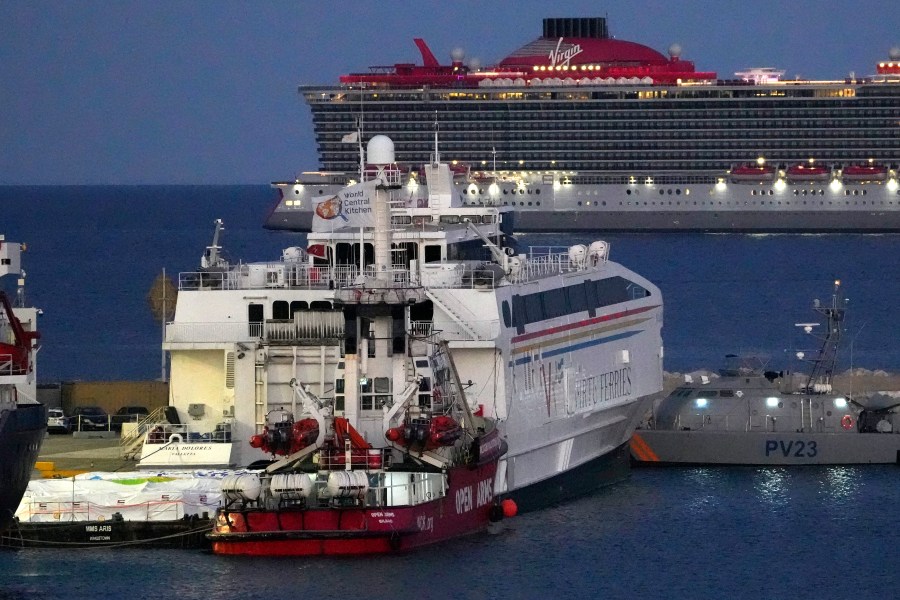 Aid packages are seen at left, on a platform near to the docked ship belonging to the Open Arms aid group, center front, as it prepares to ferry some 200 tonnes of rice and flour directly to Gaza, at the port in Larnaca, Cyprus, Monday, March 11, 2024. The European Commission president said Friday the Open Arms ship will make a pilot voyage as international donors launched a sea corridor to supply the besieged territory that is facing widespread hunger after five months of war. (AP Photo/Petros Karadjias)