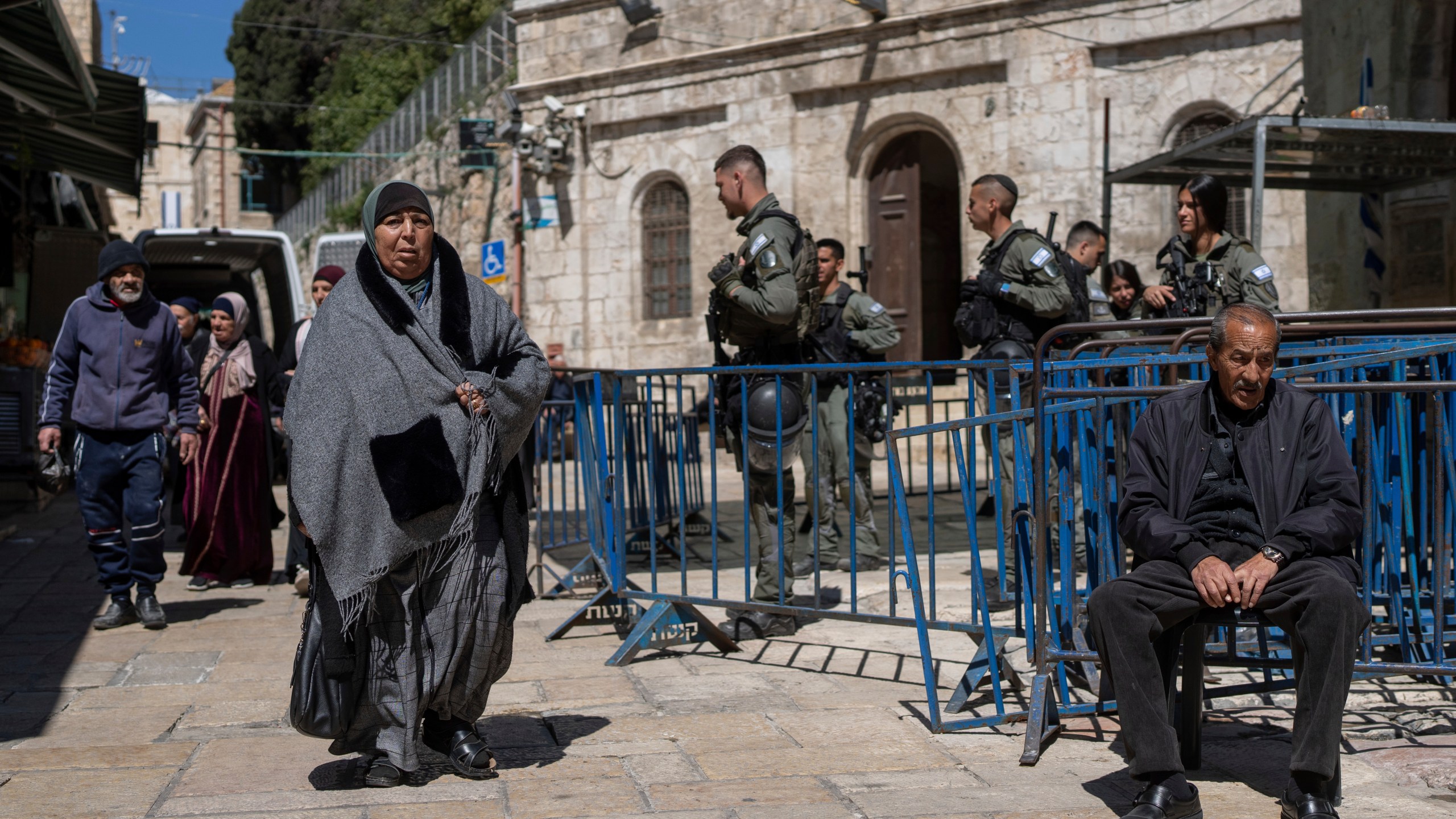 Israeli border police officers stand guard as Palestinians walk by in Jerusalem's Old City on the first day of Ramadan, Monday, March 11, 2024. (AP Photo/Ohad Zwigenberg)