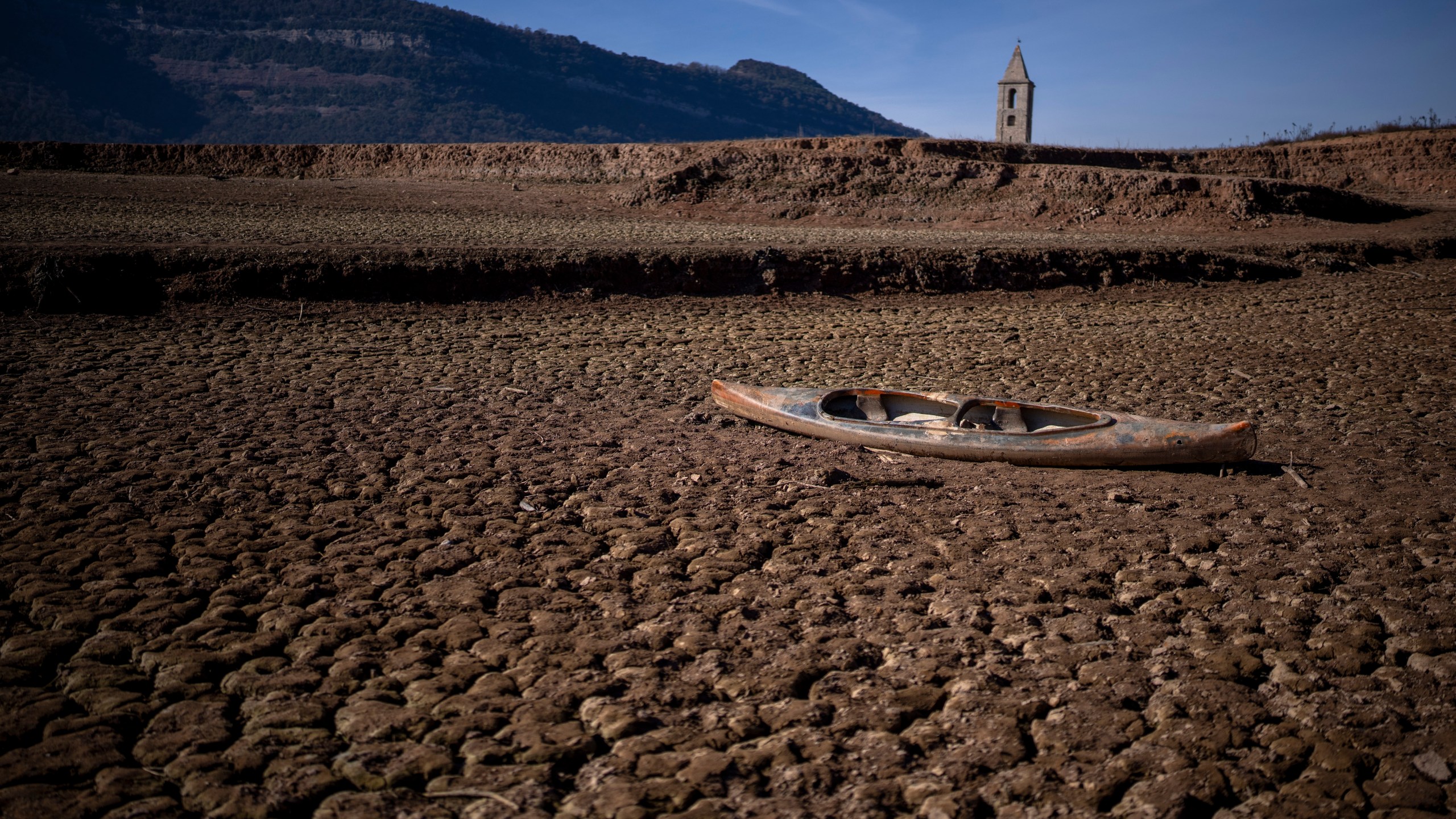 FILE - An abandoned canoe sits on the cracked ground amid a drought at the Sau reservoir, north of Barcelona, Spain, Monday, Jan. 22, 2024. Europe is facing growing climate risks and is unprepared for them, the European Environment Agency said in its first-ever risk assessment for the bloc Monday, March 11, 2024. (AP Photo/Emilio Morenatti, File)
