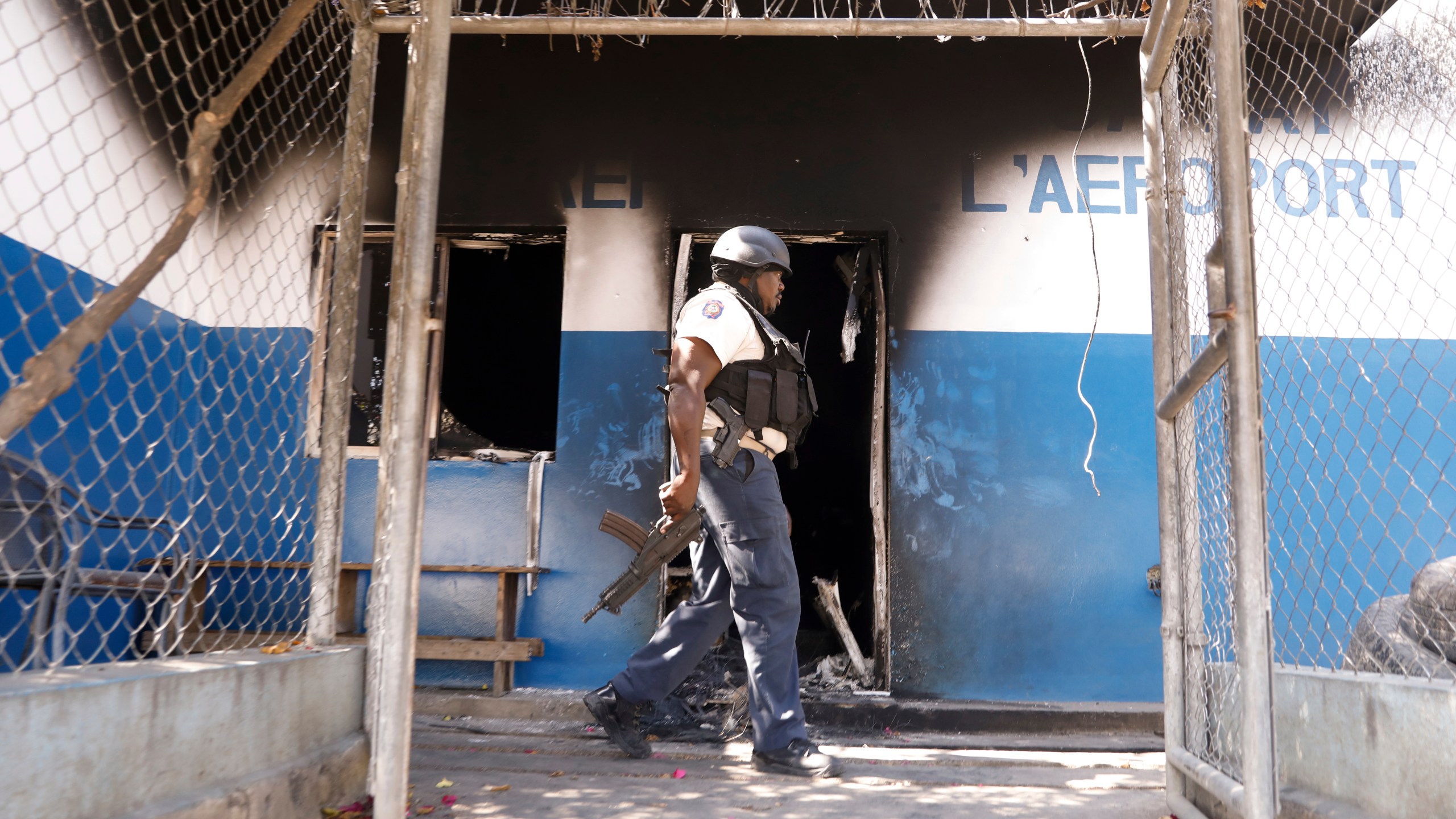 A police officer walks past a burnt out out police station set on fire by armed gangs, in Port-au-Prince, Haiti, Tuesday, March 5, 2024. (AP Photo/Odelyn Joseph)