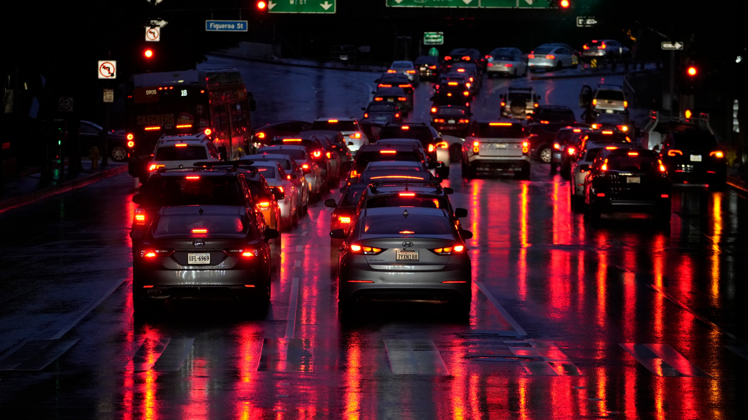 FILE - Car lights are reflected in the wet street as commuters line up in traffic to enter the I-110 Harbor freeway in the rain in downtown Los Angeles, March 6, 2024. Most electronic systems that take on some driving tasks for humans don’t adequately make sure drivers are paying attention, and they don’t issue strong enough warnings to make drivers behave. That's according to an insurance industry study published Tuesday, March 12, 2024. (AP Photo/Damian Dovarganes, File)