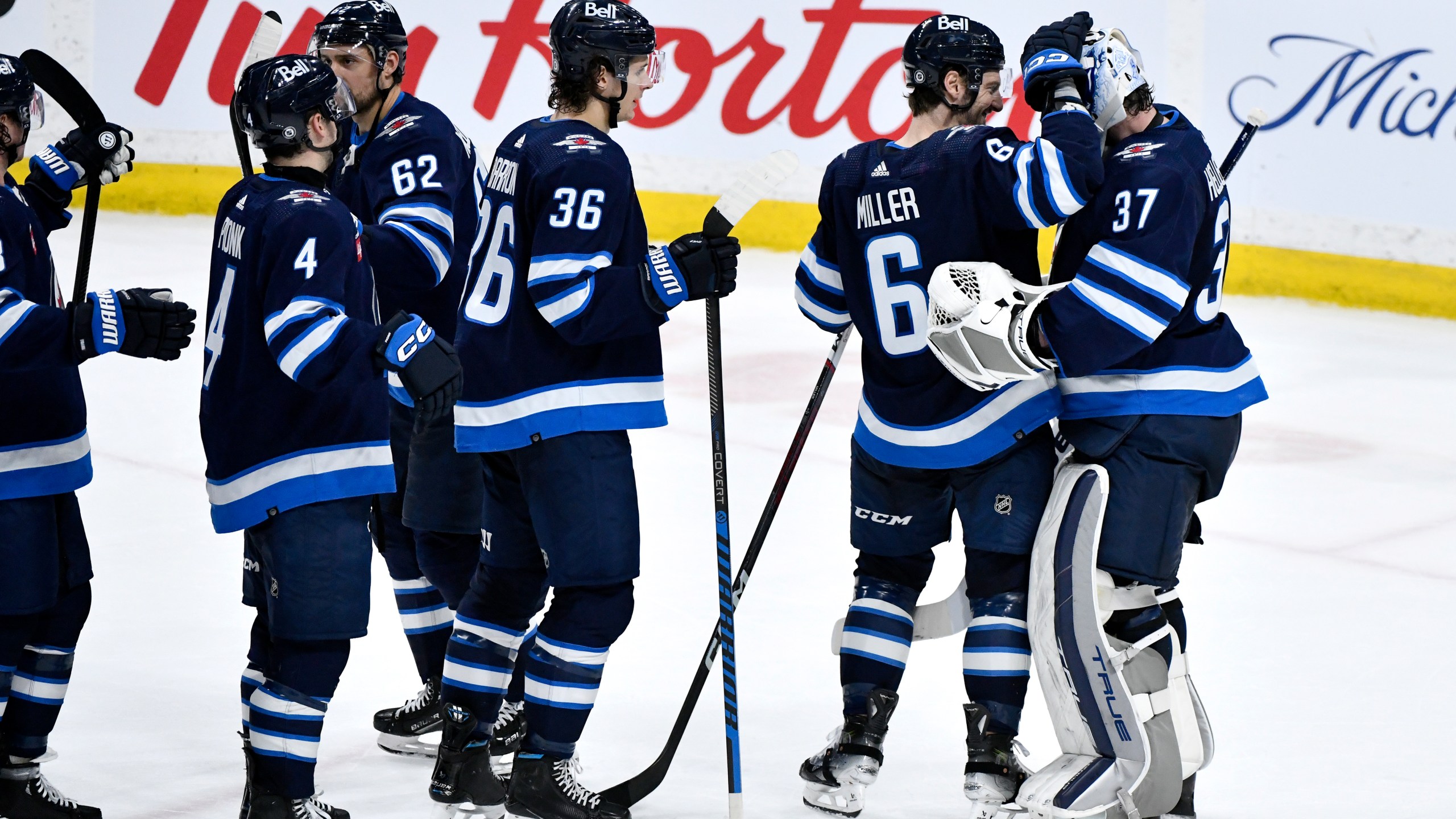 Winnipeg Jets goaltender Connor Hellebuyck (37) celebrates after his shutout against the Washington Capitals with Colin Miller (6) and other teammates after an NHL hockey game in Winnipeg, Manitoba, Monday March 11, 2024. (Fred Greenslade/The Canadian Press via AP)