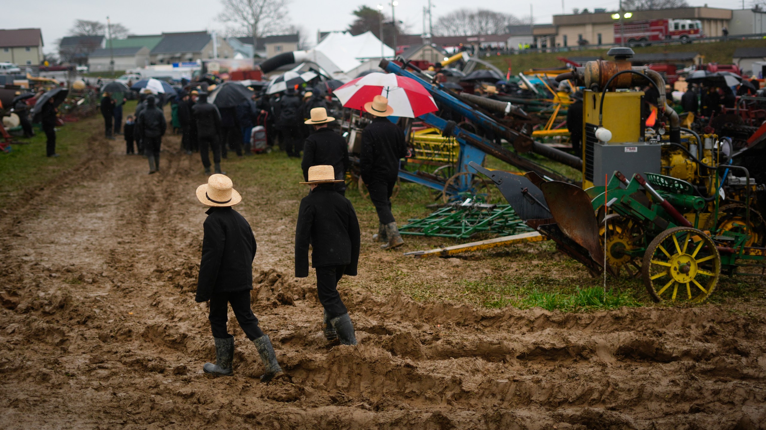 People walk in mud during an auction at the 56th annual mud sale to benefit the local fire department in Gordonville, Pa., Saturday, March 9, 2024. Mud sales are a relatively new tradition in the heart of Pennsylvania's Amish country, going back about 60 years and held in early spring as the ground begins to thaw but it's too early for much farm work. (AP Photo/Matt Rourke)