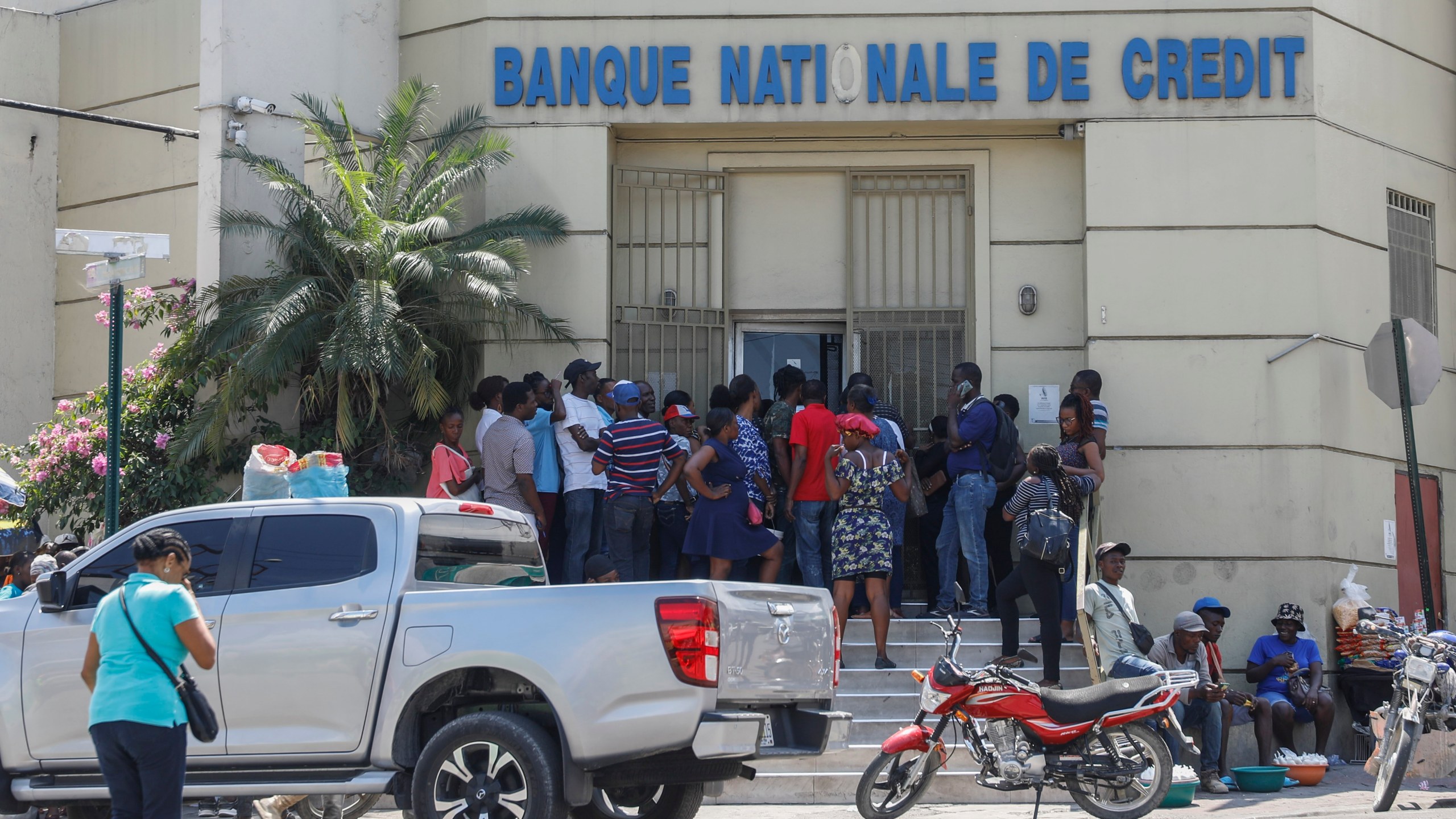 People line up outside a bank that had been closed for several days due to the violence, in Port-au-Prince, Haiti, Wednesday, March 13, 2024. (AP Photo/Odelyn Joseph)