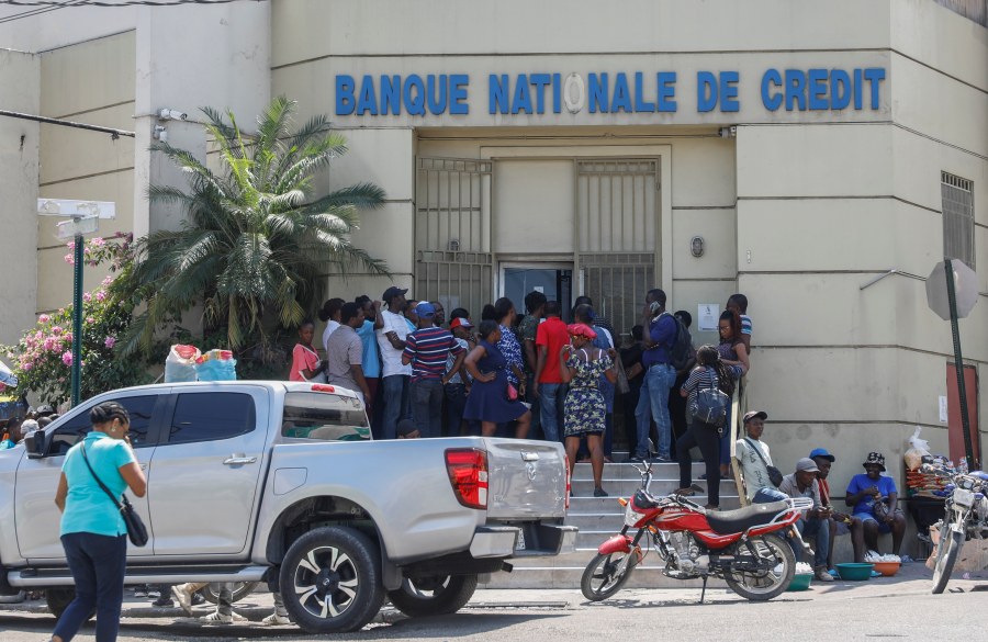 People line up outside a bank that had been closed for several days due to the violence, in Port-au-Prince, Haiti, Wednesday, March 13, 2024. (AP Photo/Odelyn Joseph)