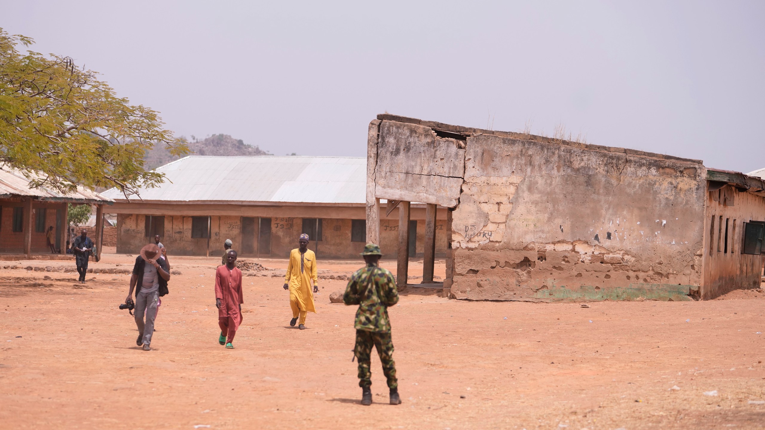Shehu Lawal, right in yellow robe, whose 13-year-old son is among those abducted at the LEA Primary and Secondary School, walks back home after visiting the school in Kuriga, Kaduna, Nigeria, Saturday, March 9, 2024. The kidnapping on Thursday was only one of three mass kidnappings in northern Nigeria since late last week, a reminder of the security crisis that has plagued Africa's most populous country. No group claimed responsibility for any of the abductions but two different groups are blamed. (AP Photo/Sunday Alamba)