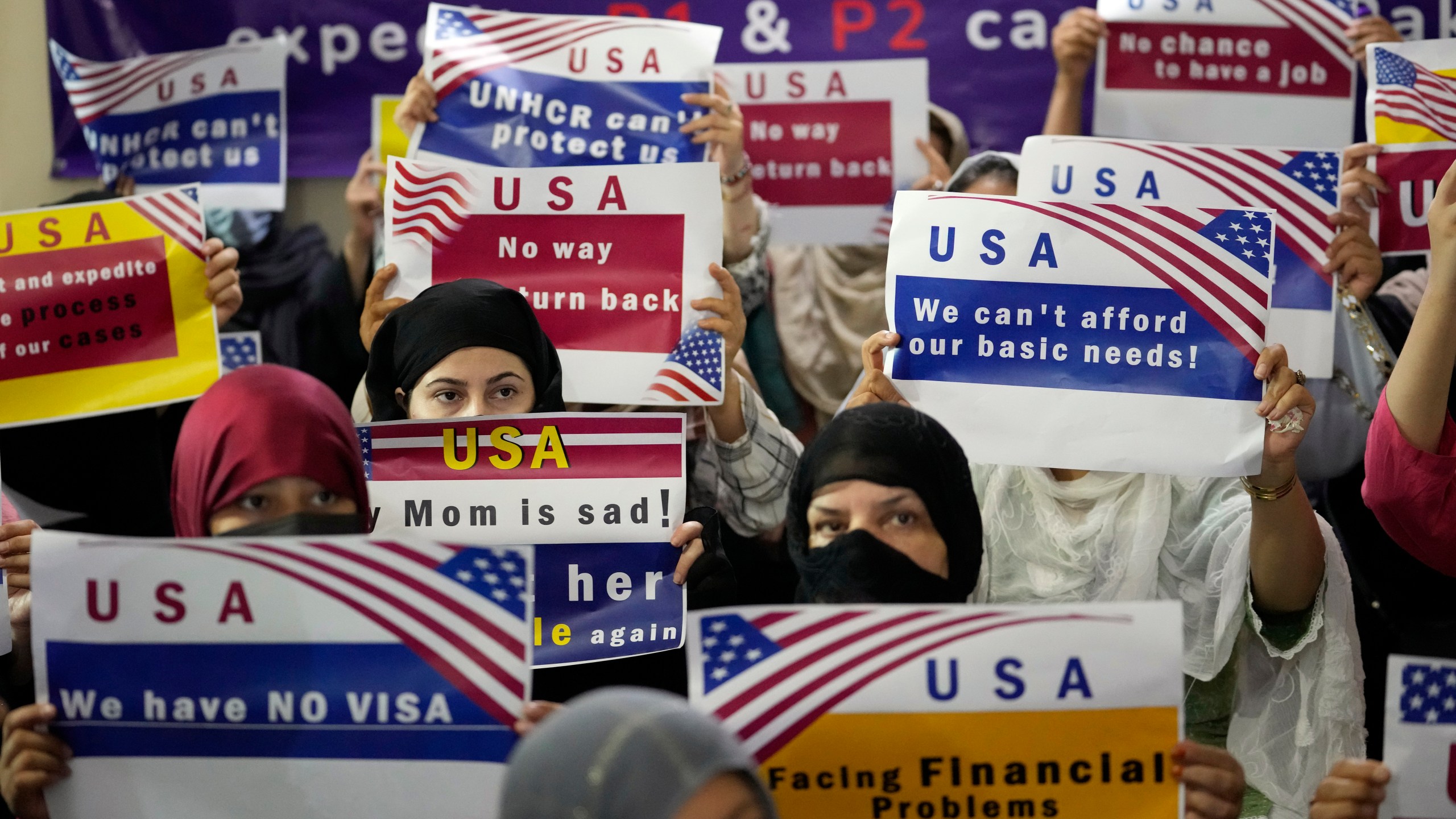 FILE - Afghan refugees hold placards during a gathering in Islamabad, Pakistan, July 21, 2023. Senators from both parties are urging congressional leaders to ensure that more visas are made available to Afghans who worked alongside U.S. troops in America's longest war. The senators say an additional 20,000 visas are needed before the end of the fiscal year in September. (AP Photo/Rahmat Gul, File)