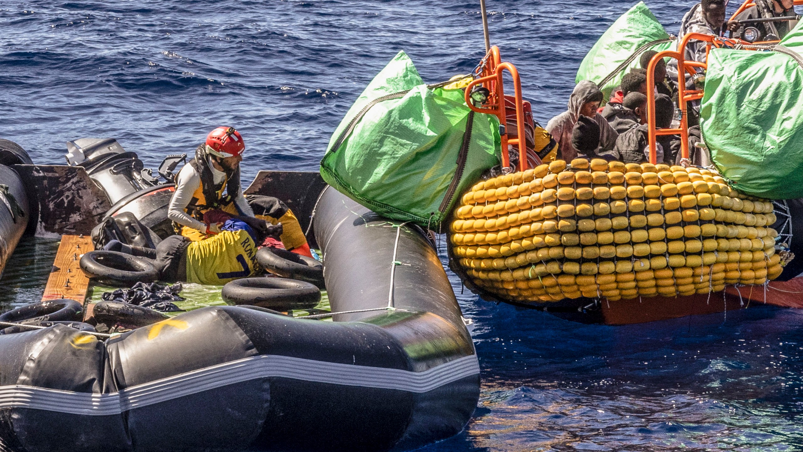 A migrant is helped evacuate a partially deflated rubber dinghy by the rescue personnel of the SOS Mediterranee humanitarian ship Ocean Viking in the Central Mediterranean Sea, Wednesday, March 13, 2024, Survivors reported that some 50 people who departed Libya with them a week ago had perished during the journey. (Johanna de Tessieres/ SOS Mediterranee via AP, HO)