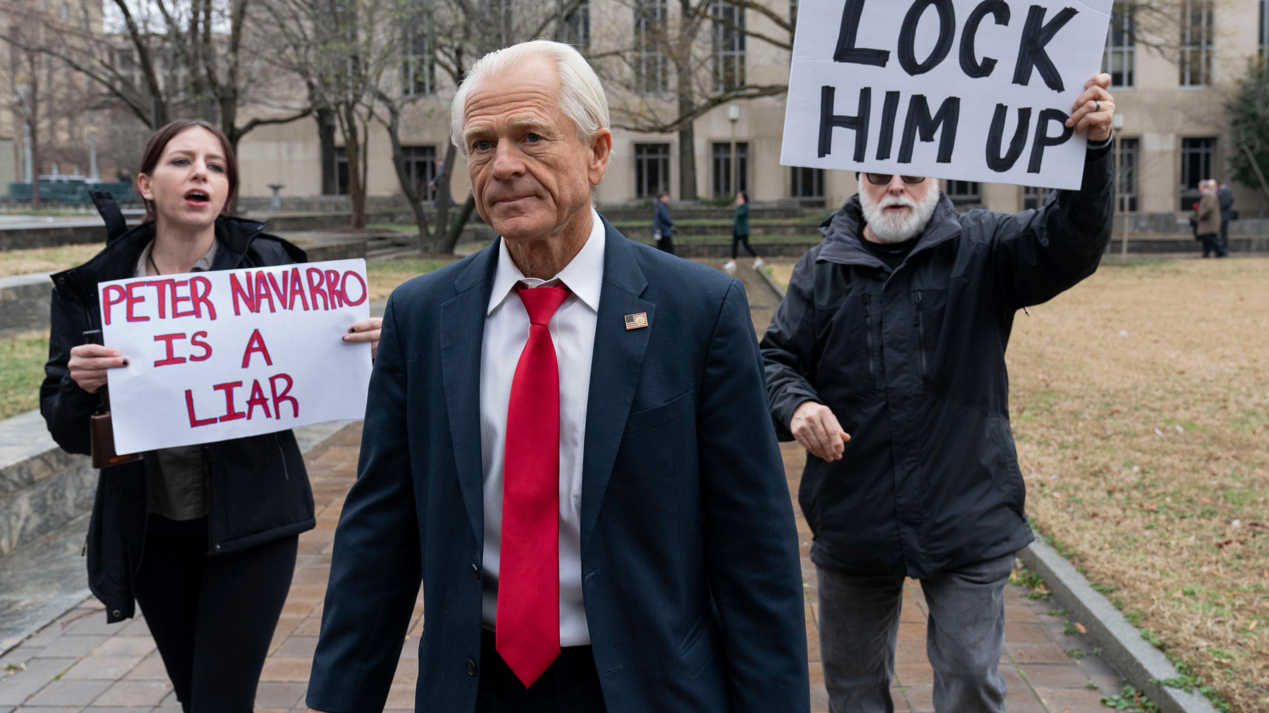 FILE - Former Trump White House official Peter Navarro, followed by demonstrators, leaves the U.S. Federal Courthouse in Washington, Jan. 25, 2024. An appeals court Thursday, March 14, denied Navarro’s bid to stave off his jail sentence on contempt of Congress charges for refusing to cooperate with a congressional investigation into the Jan. 6, 2021, attack on the U.S. Capitol. Navarro has been ordered to report to a federal prison by March 19. (AP Photo/Jose Luis Magana, File)