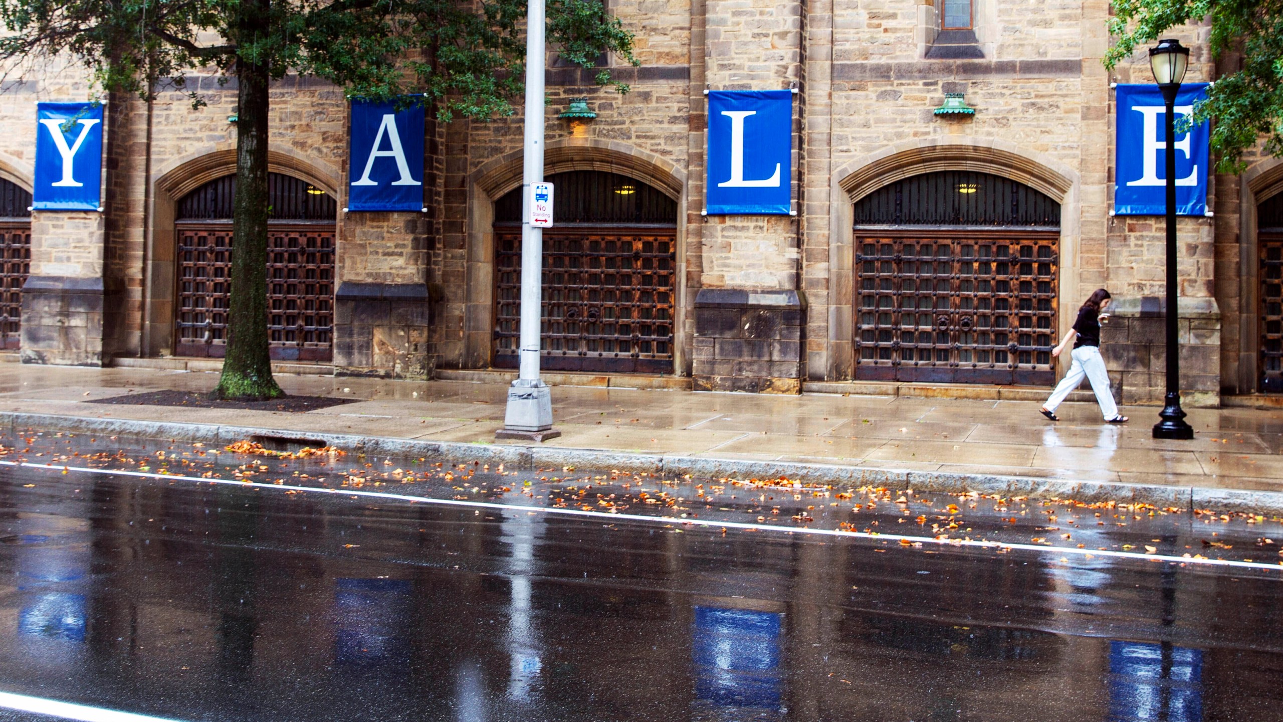 FILE - A woman walks by a Yale sign reflected in the rainwater on the Yale University campus, Aug. 22, 2021, in New Haven, Conn. Connecticut lawmakers are considering banning the use of legacy and donor preferences in admissions to all colleges and universities across the state, including private ones like Yale University. (AP Photo/Ted Shaffrey, File)